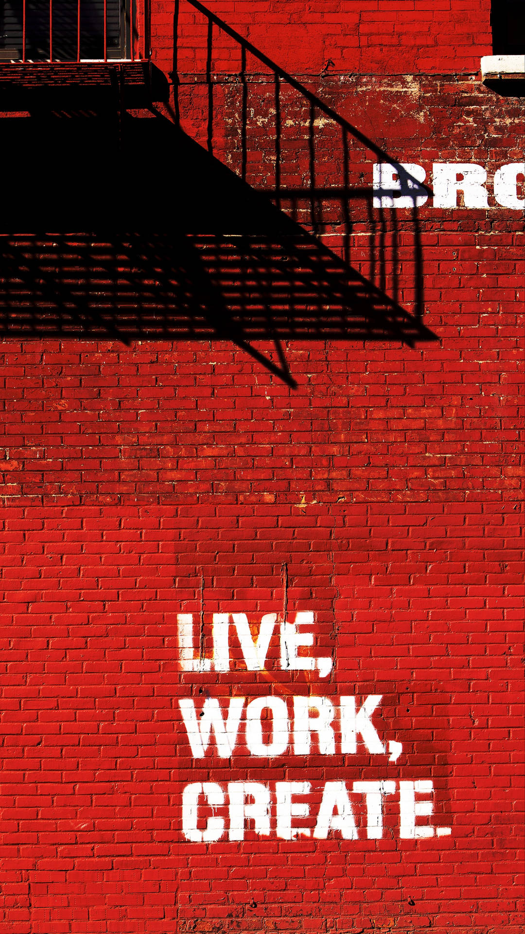 紅色磚牆上帶有白色文字 live work create 和黑色防火梯陰影。 — Note 10 Plus 壁紙