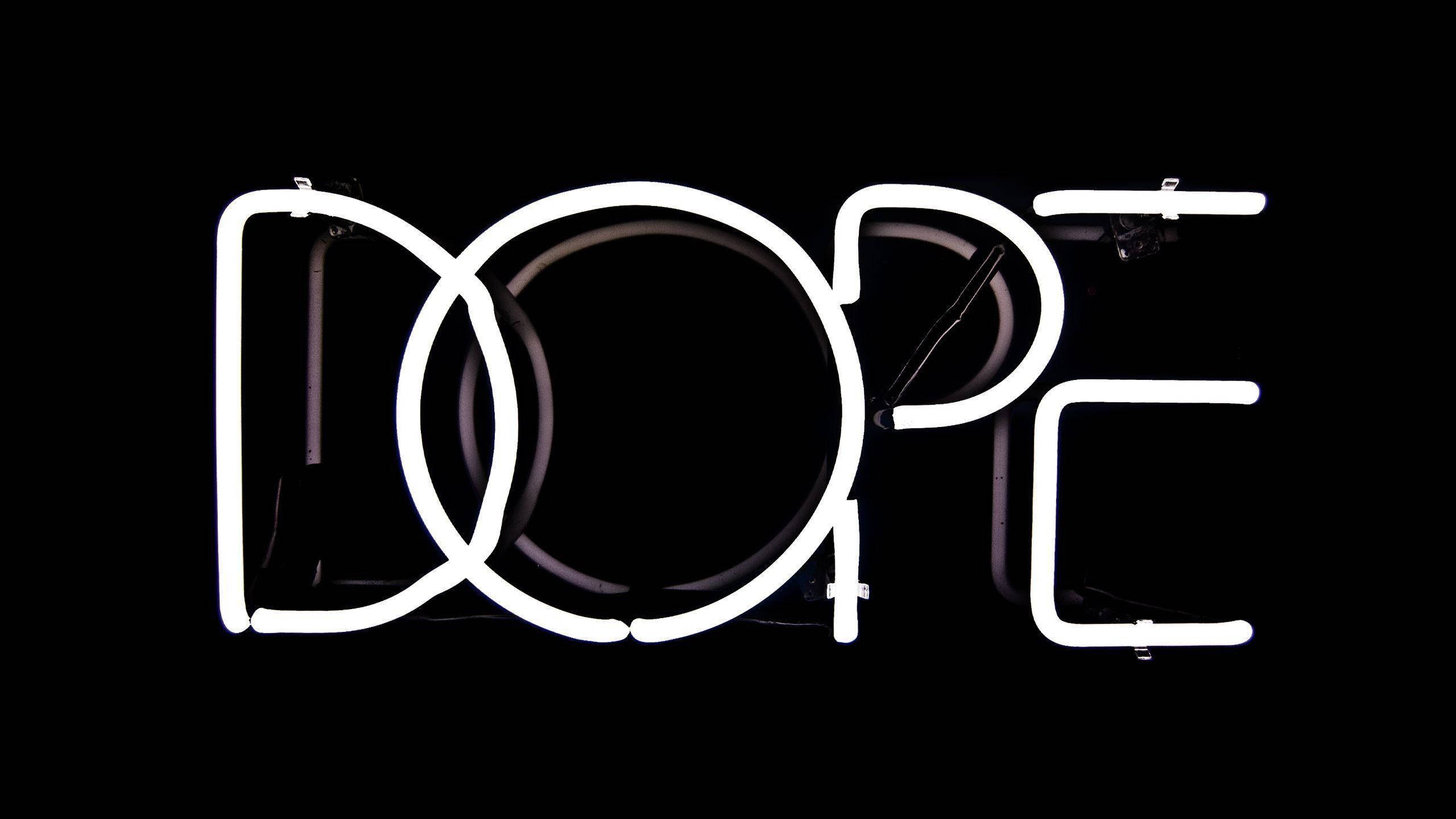 超炫動圖 桌布 壁紙 — 大膽的白色霓虹燈牌拼出 'DOPE'，在純黑色背景上發光，可見燈管和安裝硬件。