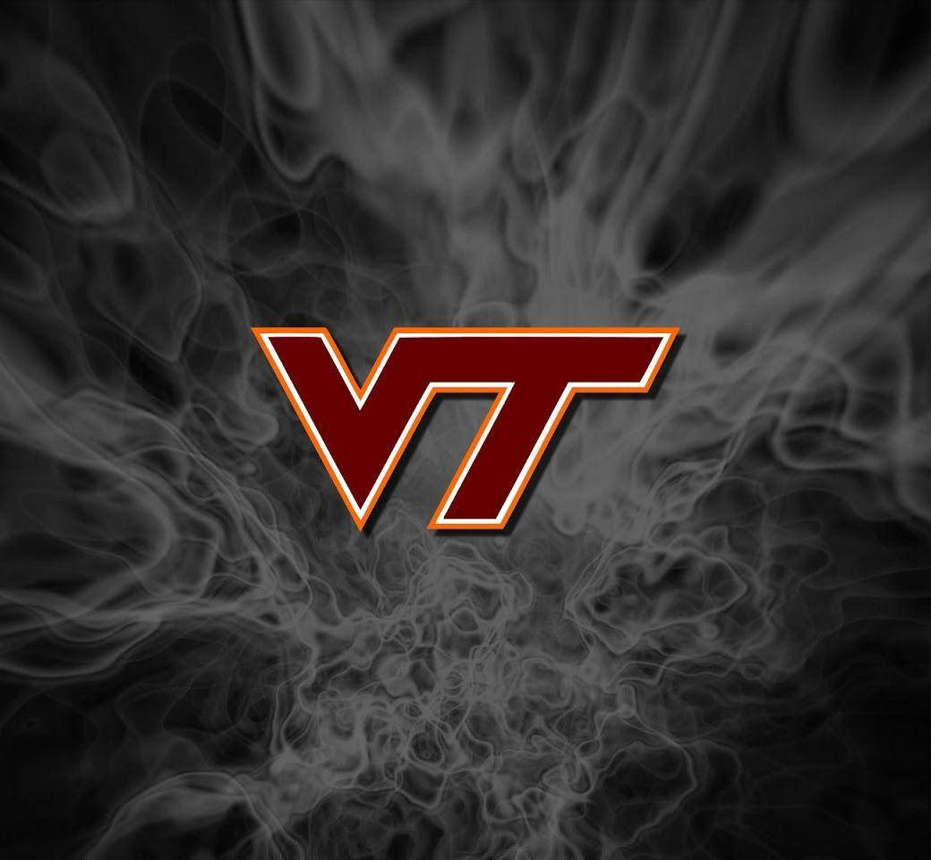 Virginia Tech 桌布 壁紙 — 大膽的紅色VT標誌配金色邊飾從深色背景上的旋轉灰色煙霧中浮現。