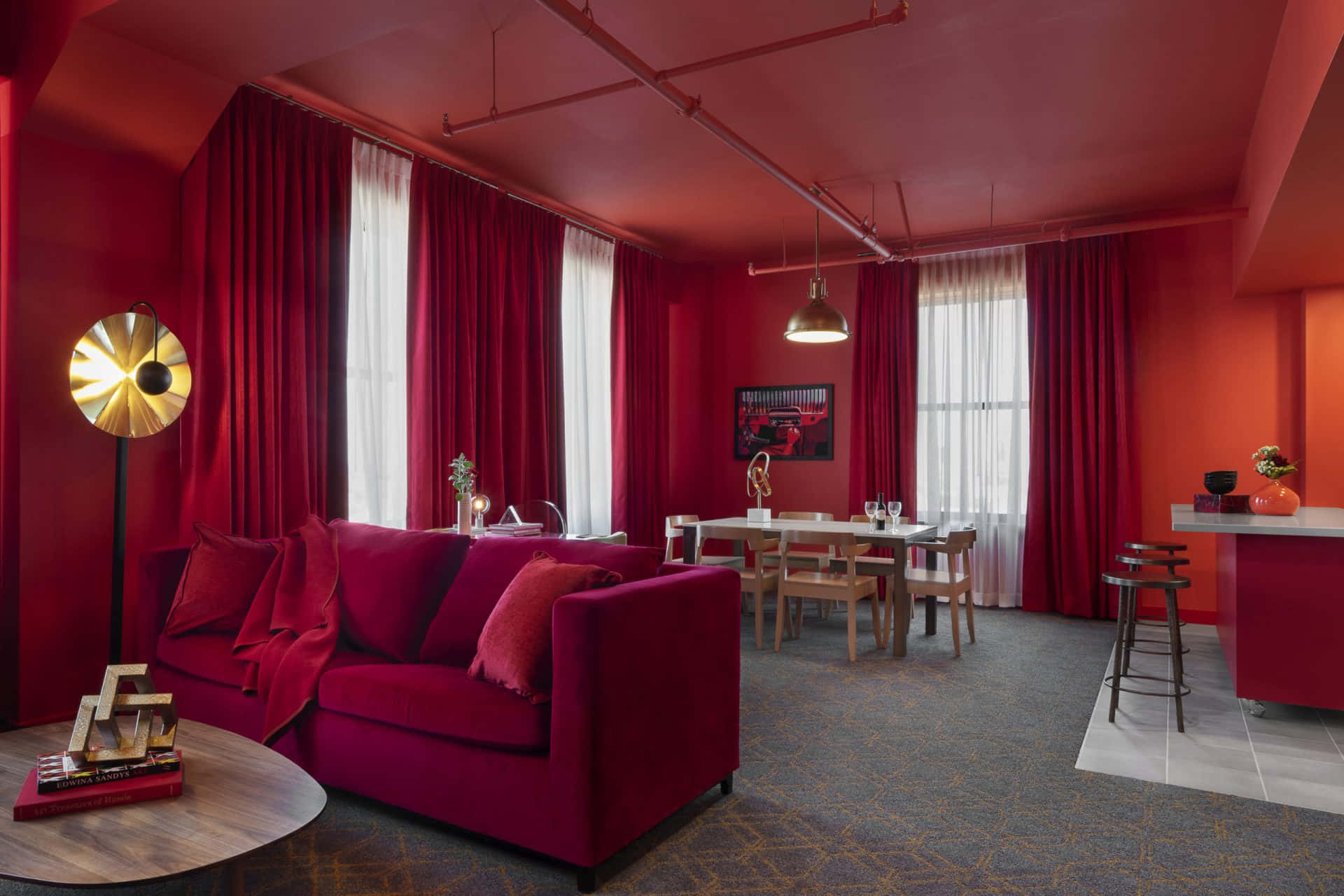 Red Room 桌布 壁紙 — 大膽的紅色室內設計，配有天鵝絨沙發、餐桌和裸露管道，沐浴在溫暖的燈光中。