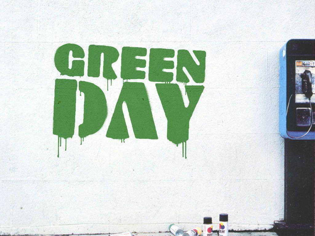 Green Day 桌布 壁紙 — 大膽的綠色塗鴉拼寫GREEN DAY，滴落在白色混凝土牆上，旁邊有一個藍色公用電話和噴漆罐。