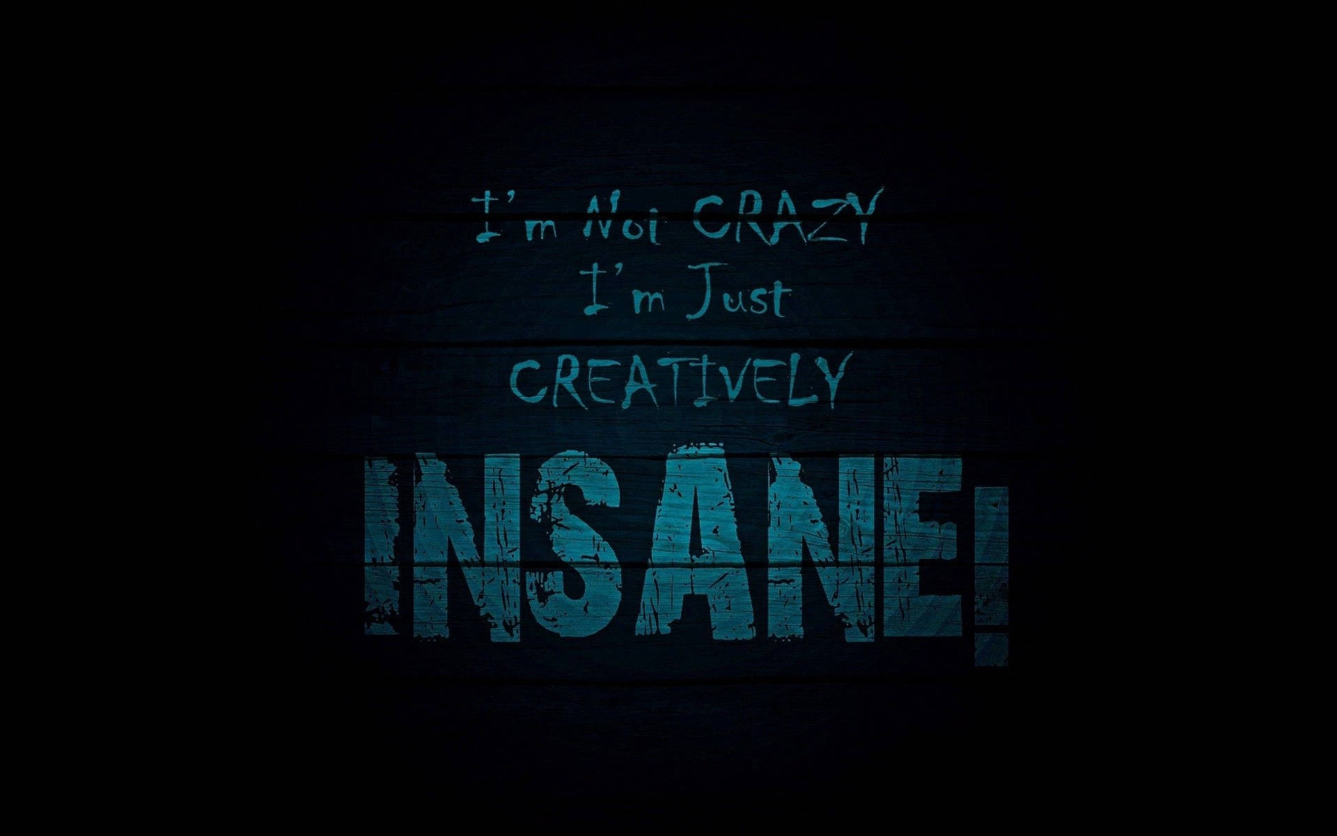 深色木材上的藍色塗鴉風格文字寫著「I'm Not Crazy I'm Just Creatively Insane!」。 — 深色引言 壁紙