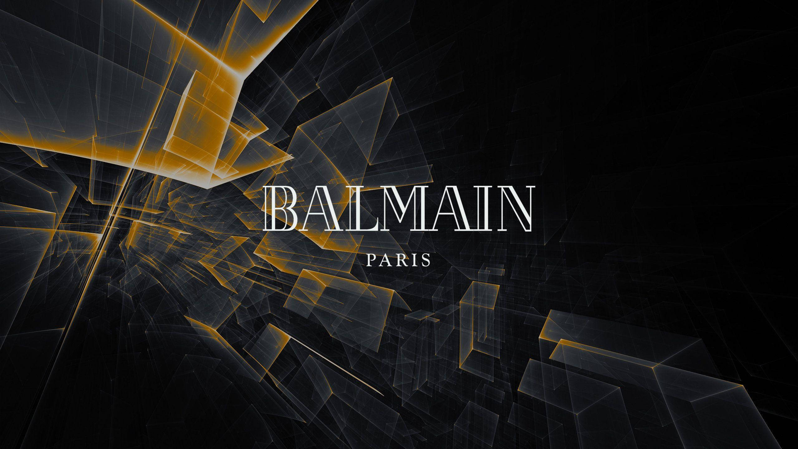 桌布 壁紙 — 大膽的金色和黑色幾何碎片在 Balmain Paris 標誌後方放射，展現銳利的現代優雅。