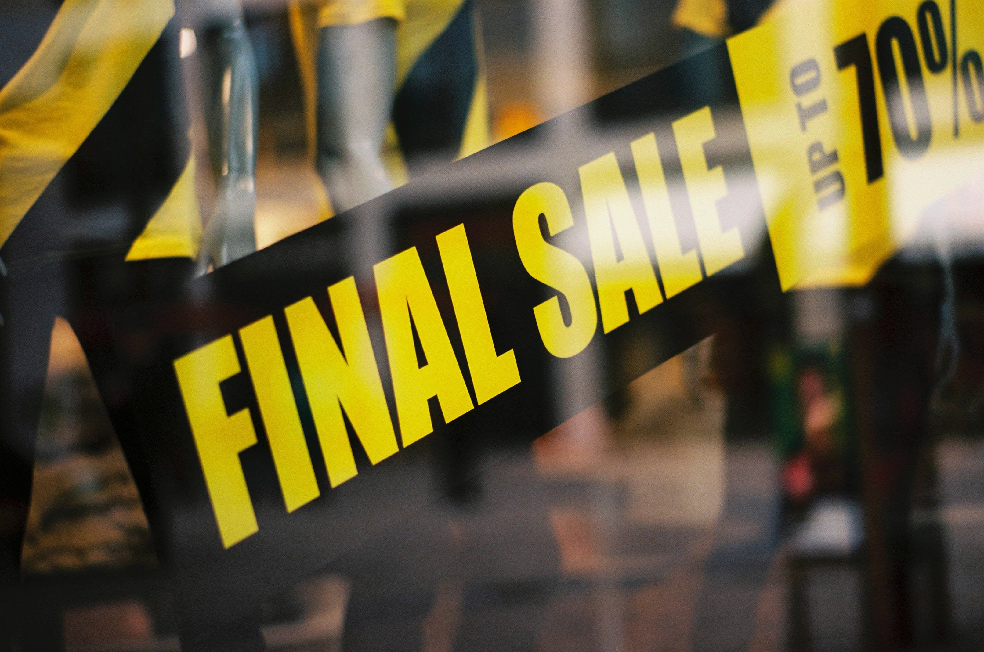 Sales 桌布 壁紙 — 大膽的黃色和黑色「FINAL SALE」標誌貼在商店櫥窗上，背景有模糊的人體模型。