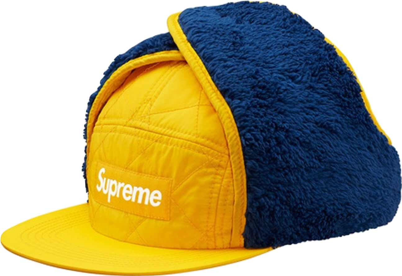 supreme 桌布 壁紙 — 大膽的黃藍色絎縫 Supreme 帽子，帶有蓬鬆羊毛飾邊和白色標誌，黑色背景。