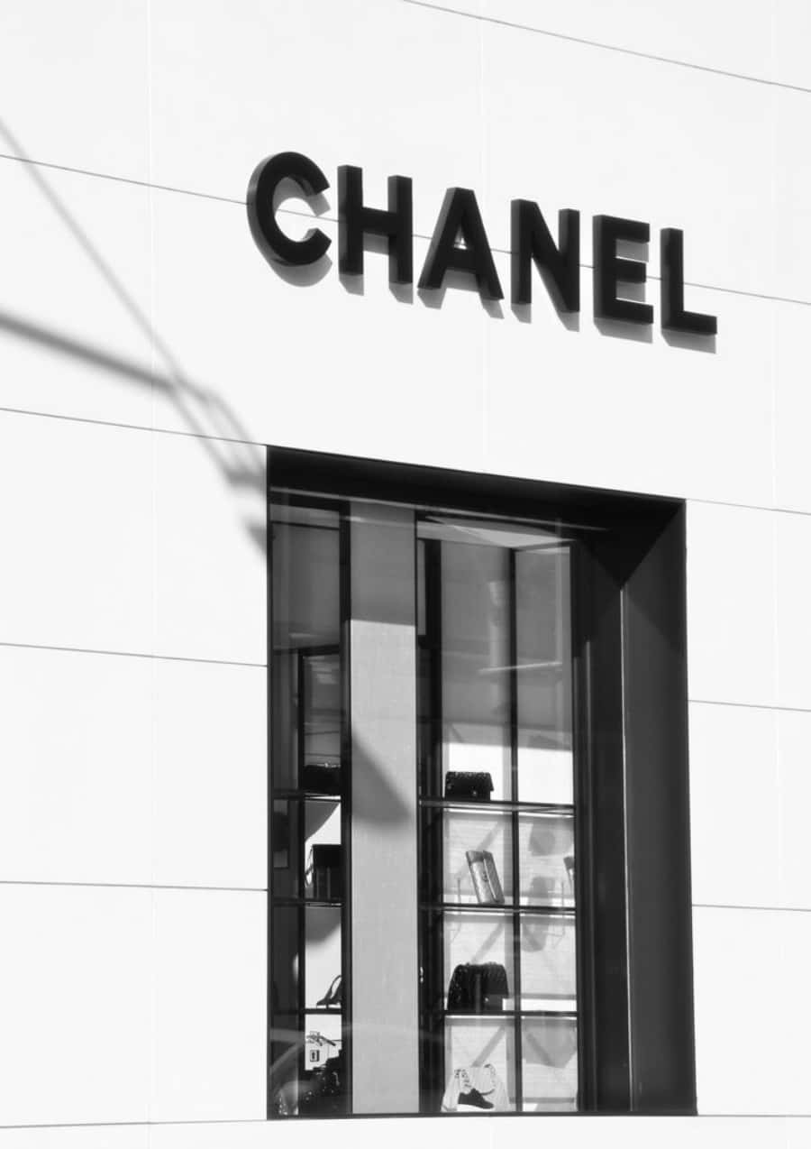 Chanel 桌布 壁紙 — 大膽的黑色CHANEL標誌在玻璃展示窗上方的純白外牆上投下銳利陰影。
