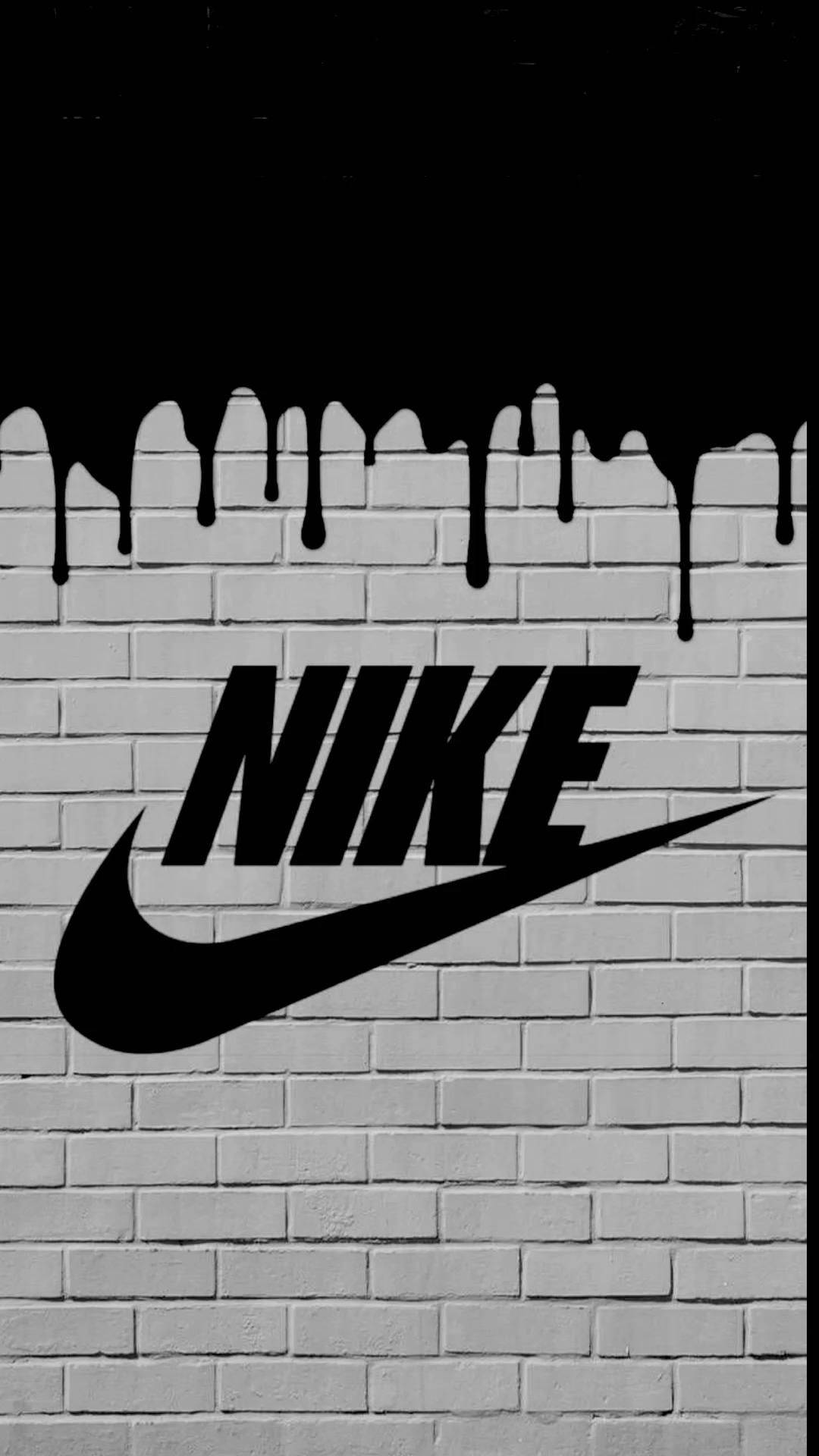 Nike 桌布 壁紙 — 大膽的黑色Nike標誌以鮮明的單色塗鴉風格滴落在白色磚牆上。