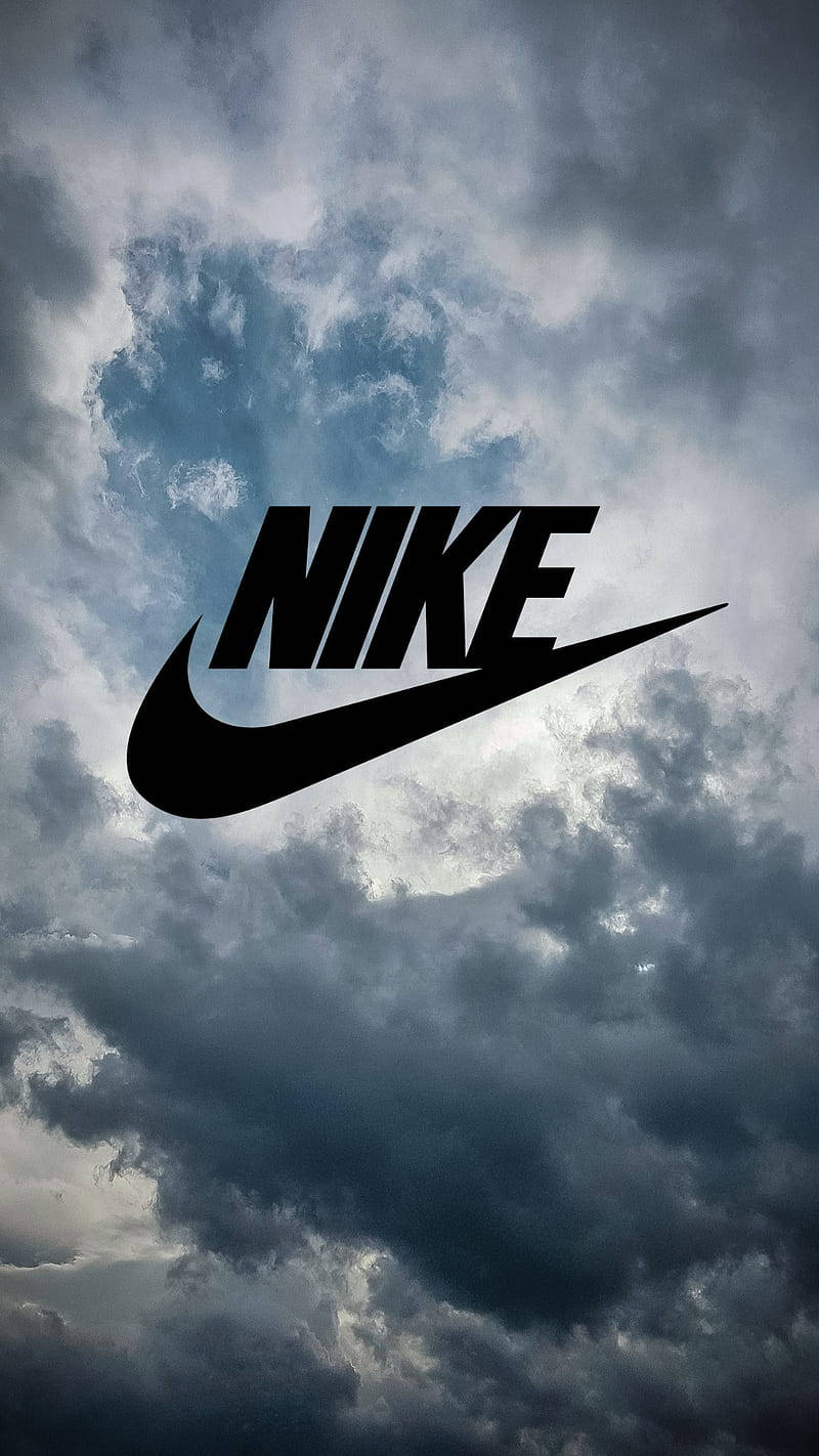 Swoosh 桌布 壁紙 — 大膽的黑色Nike標誌漂浮在充滿旋轉灰色和藍色暴風雲的戲劇性天空中。