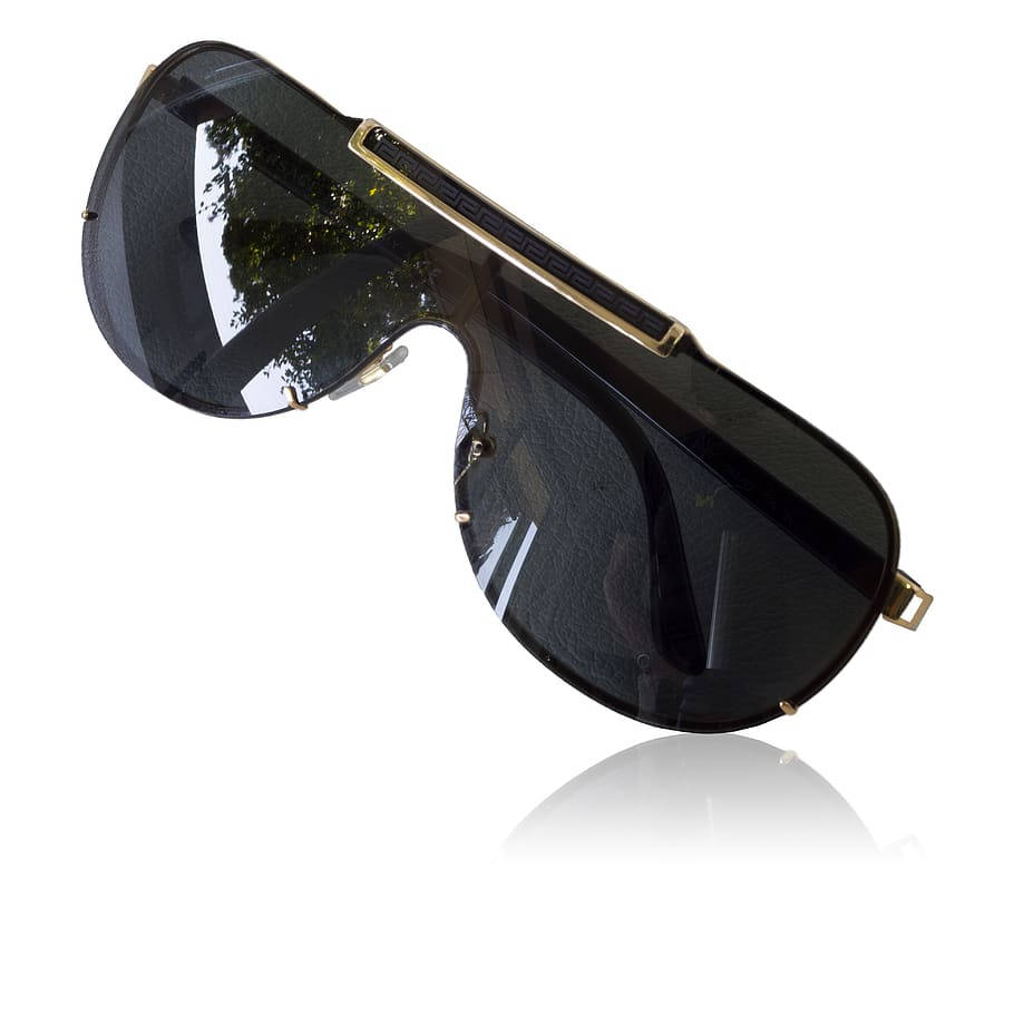 Sunglasses 桌布 壁紙 — 大膽的黑色盾形太陽眼鏡，帶有金色希臘鑰匙細節和反光鏡片，白色背景。