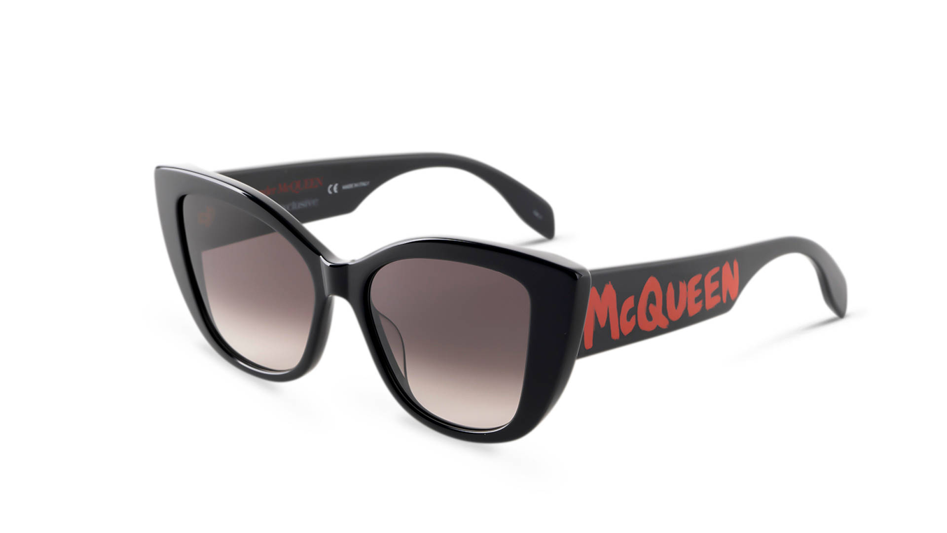 Sunglasses 桌布 壁紙 — 大膽的黑色貓眼太陽眼鏡，鏡臂上有紅色McQueen品牌標誌，置於純白背景上。