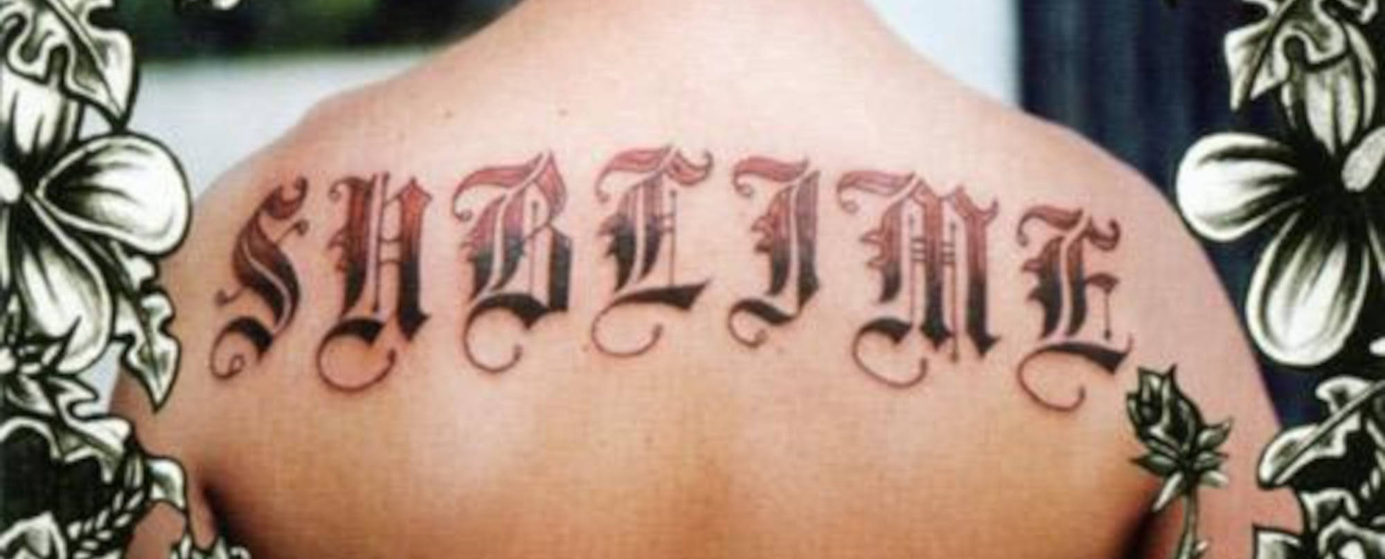 Tattoo 桌布 壁紙 — 大膽的黑體紋身，在一個人的上背部拼寫「SUBLINE」，並以大型花卉圖案框住。