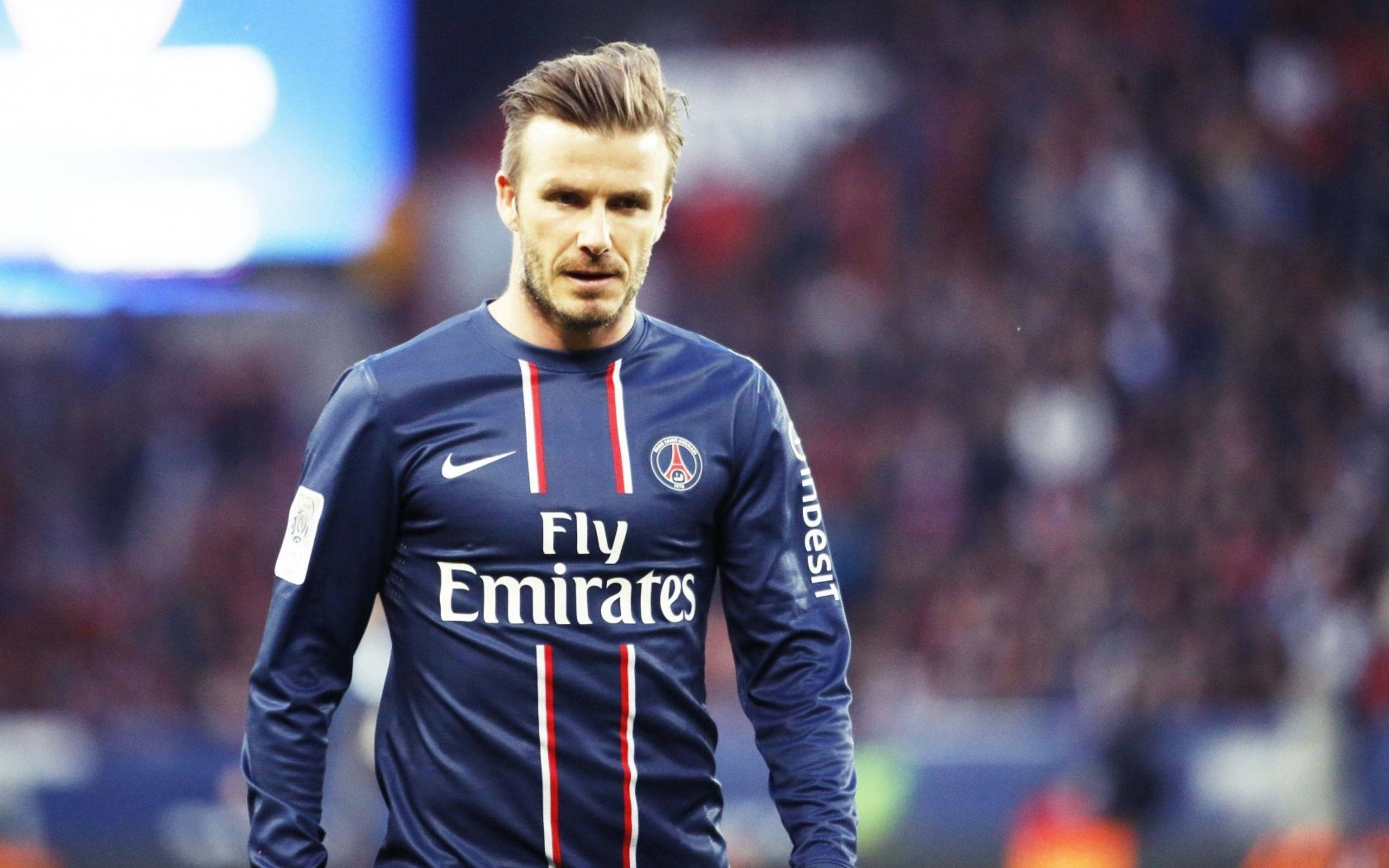 David Beckham 桌布 壁紙 — 大衛貝克漢在明亮的球場燈光下，身穿巴黎聖日耳曼足球球衣在球場上行走。