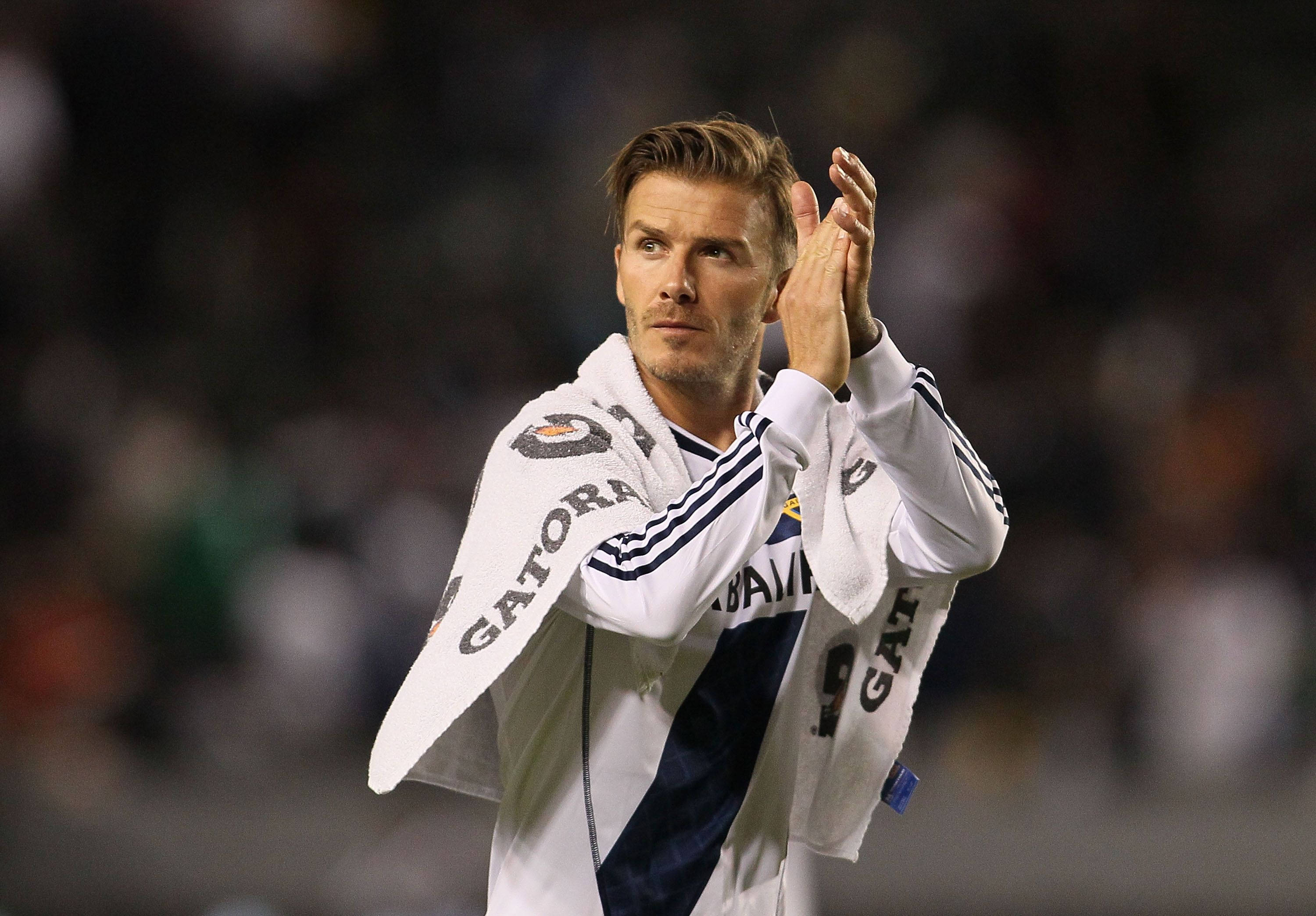 David Beckham 桌布 壁紙 — 大衛貝克漢在球場燈光下，身穿白色皇家馬德里球衣，肩上披著Gatorade毛巾，向球迷鼓掌。