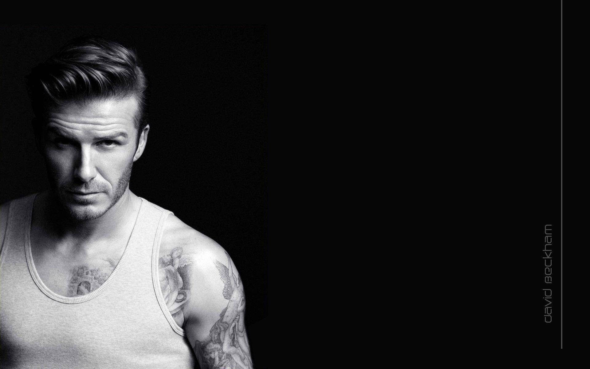 David Beckham 桌布 壁紙 — 大衛貝克漢的黑白肖像，表情強烈，手臂上的刺青在深色背景下清晰可見。
