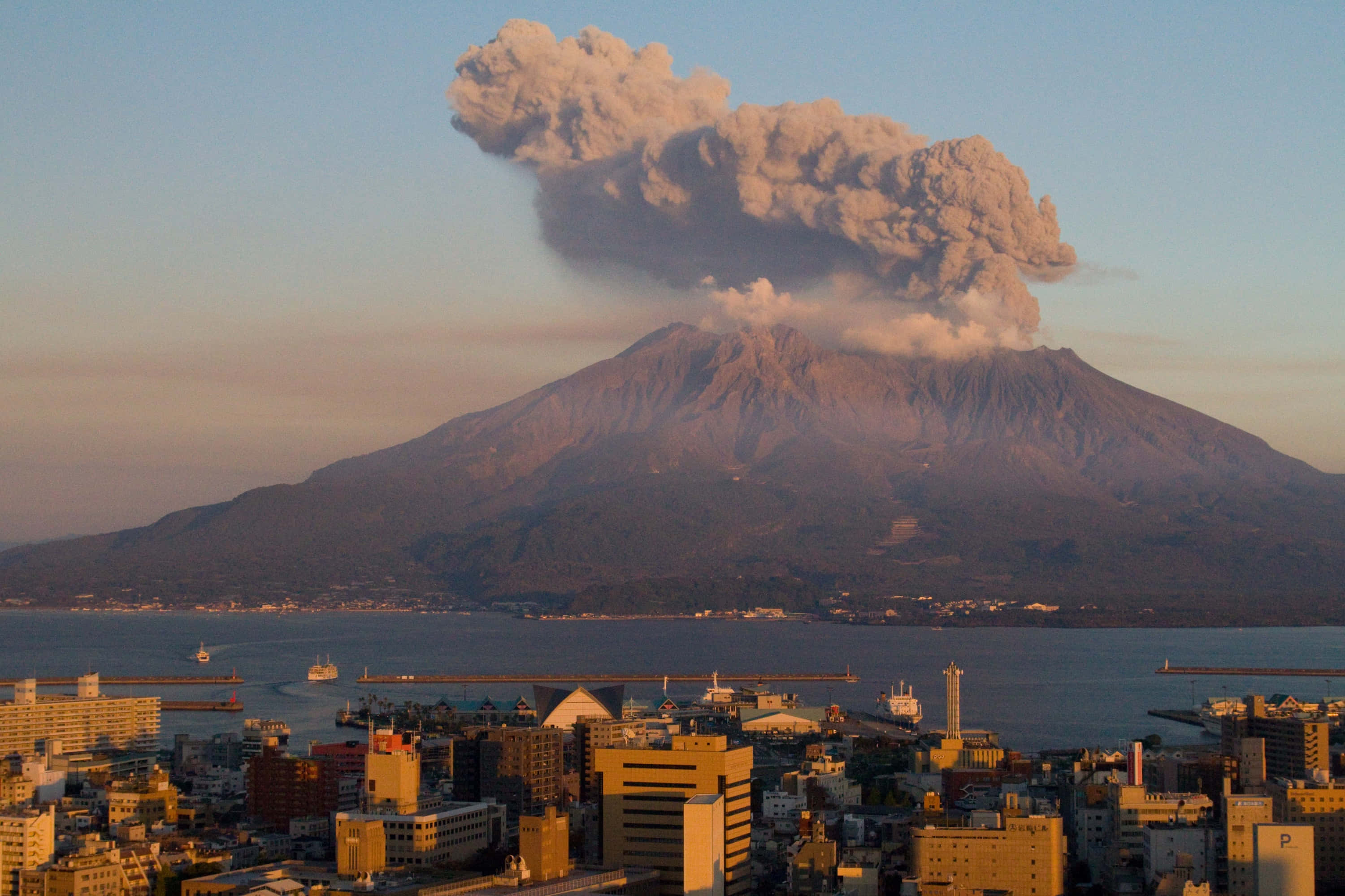 Natural Disaster 桌布 壁紙 — 大規模火山爆發，在日落時分將高聳的火山灰雲送上沿海城市上空。
