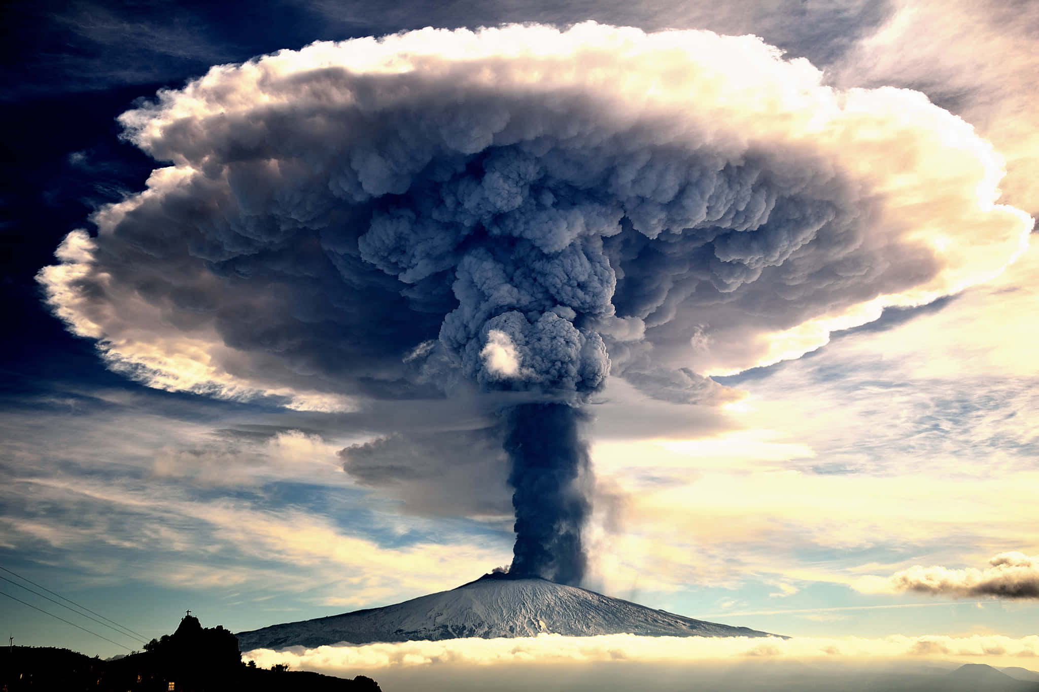 Volcano 桌布 壁紙 — 大規模火山爆發將高聳的暗色火山灰柱噴向被金色陽光照亮的戲劇性天空。