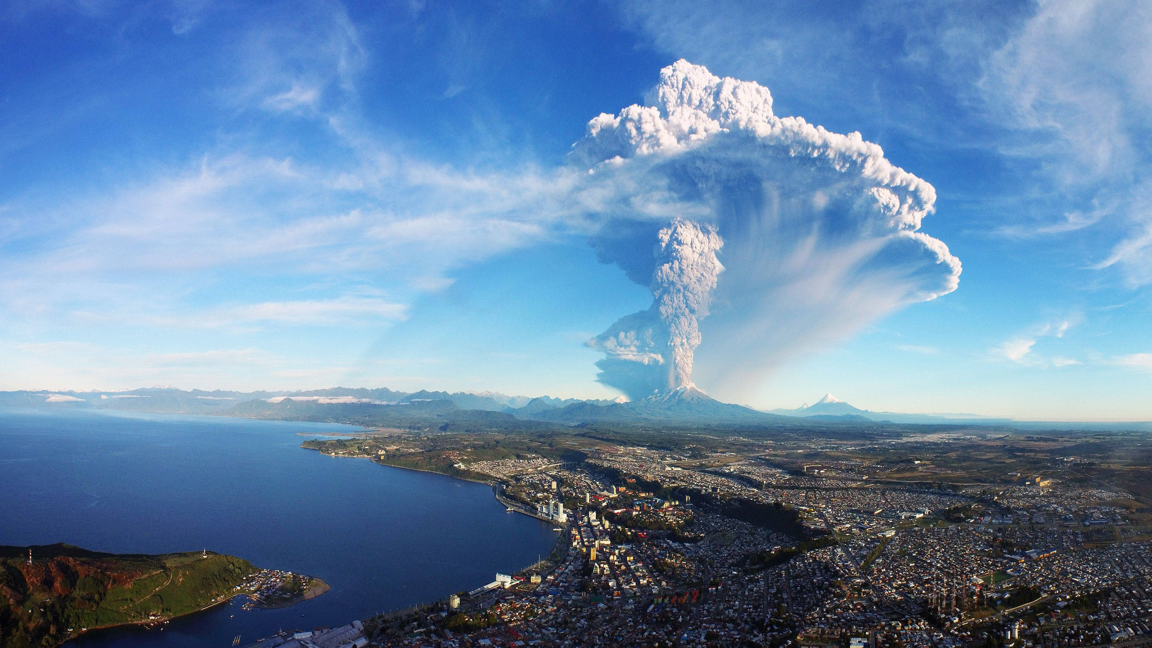 自然 桌布 壁紙 — 大規模火山爆發將高聳的火山灰柱噴向沿海城市和海洋上空的晴朗藍天。