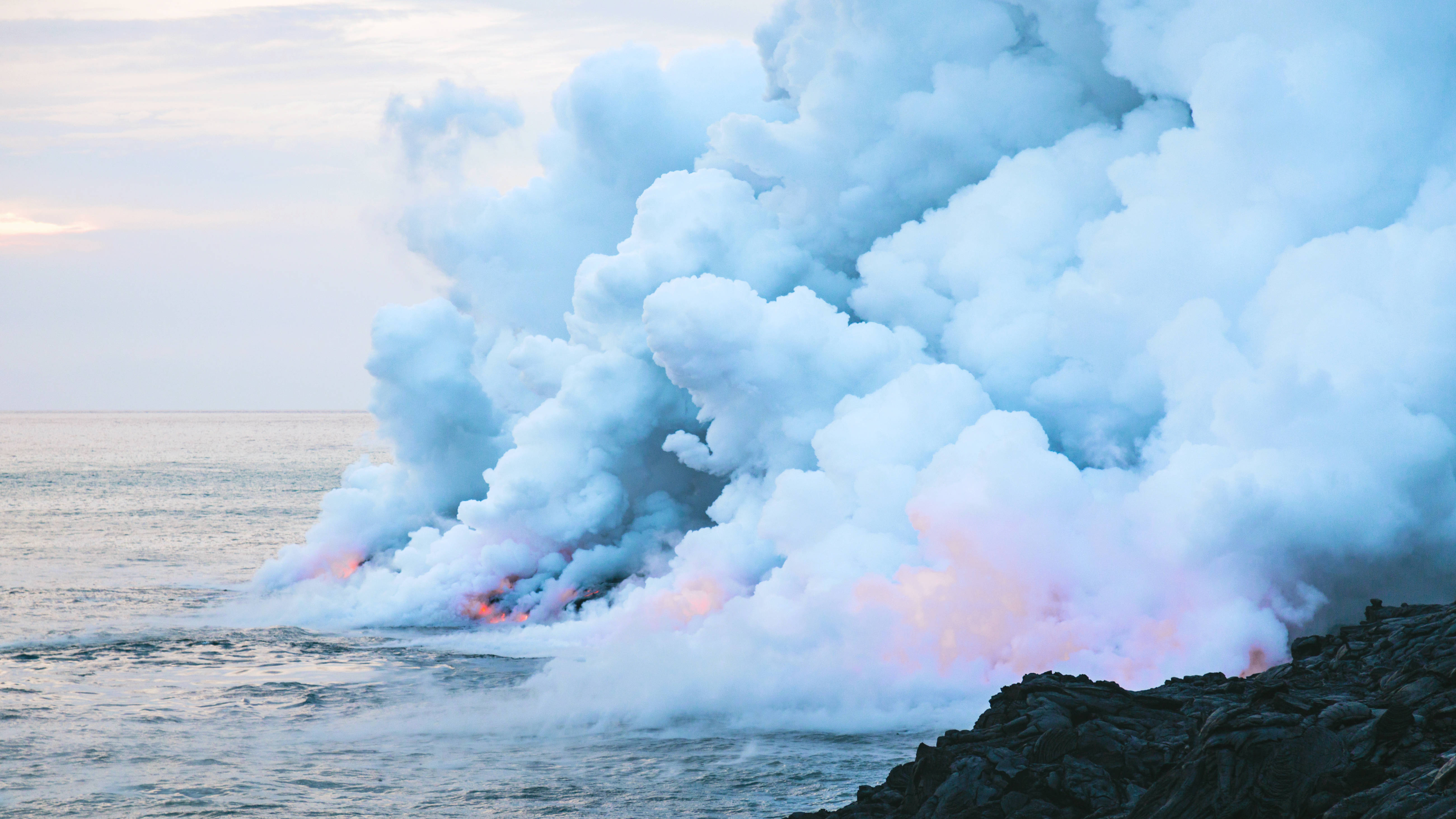 Blue Smoke 桌布 壁紙 — 大量蒸氣和煙霧從火山口噴出，與海洋相遇，下方有發光的橙色熔岩。