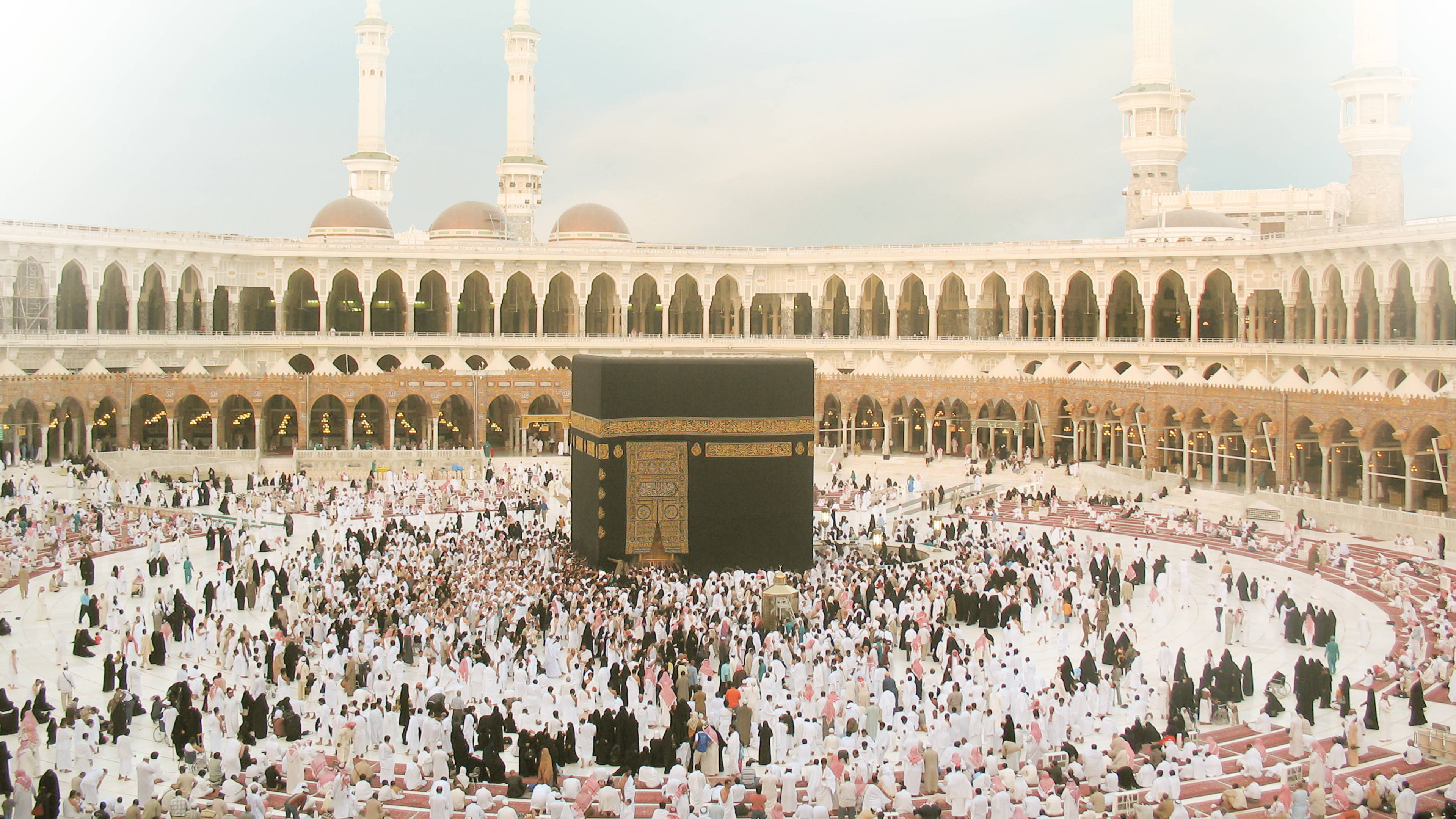 muslim 桌布 壁紙 — 大量身穿白衣的人群在明亮的天空下，於大清真寺內繞行黑色天房。