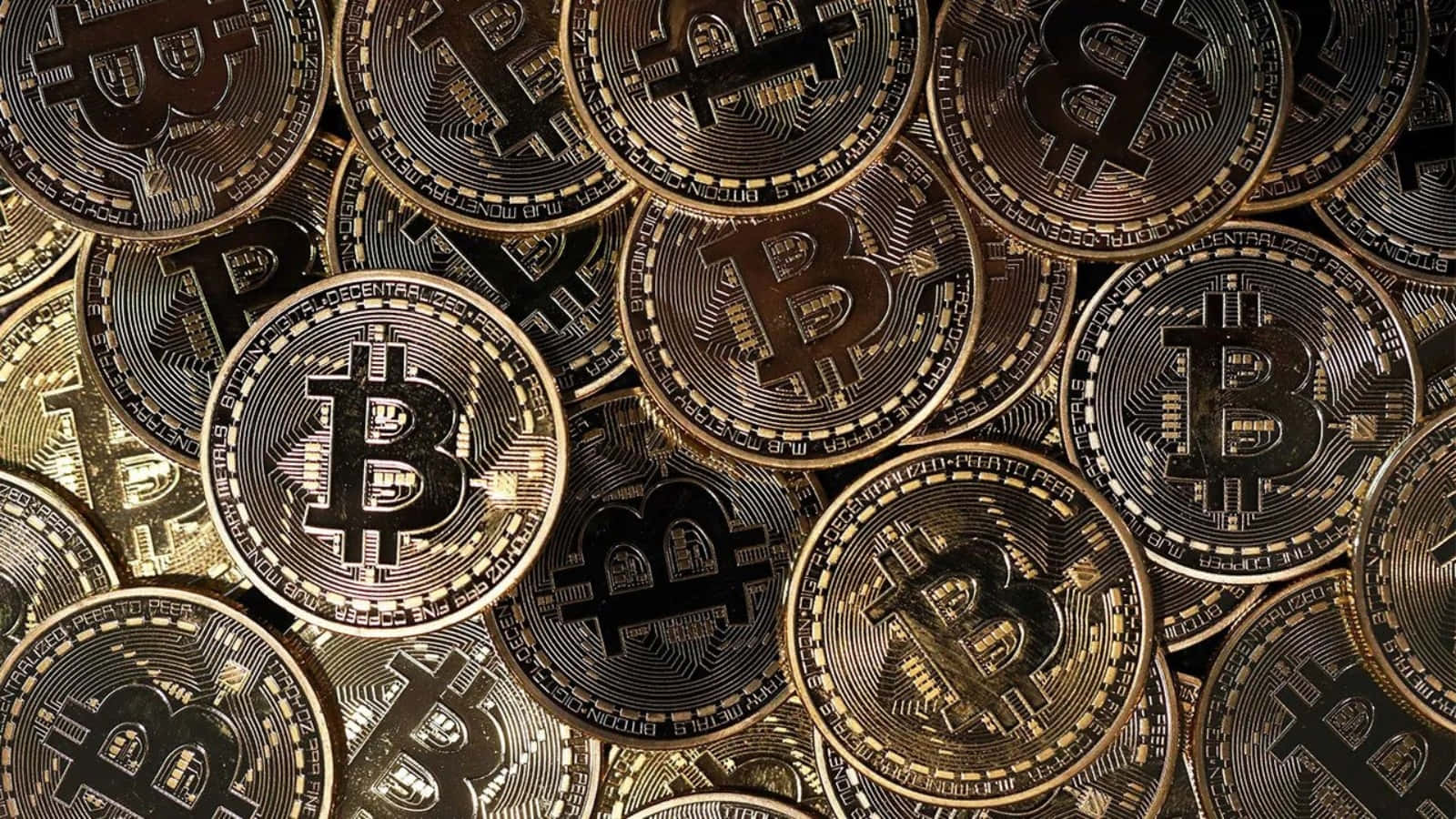 比特幣 桌布 壁紙 — 大量金色比特幣硬幣堆疊在一起的近距離特寫，展示其精細雕刻和金屬光澤。
