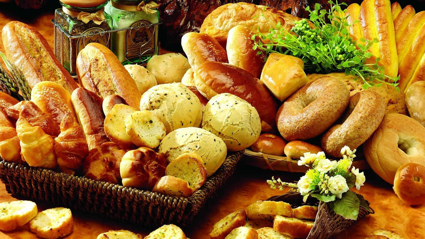 1366x768 Pastries 桌布 壁紙 — 大量金黃色的手工麵包和糕點，整齊地擺放在編織籃中，並以新鮮香草和鮮花點綴。