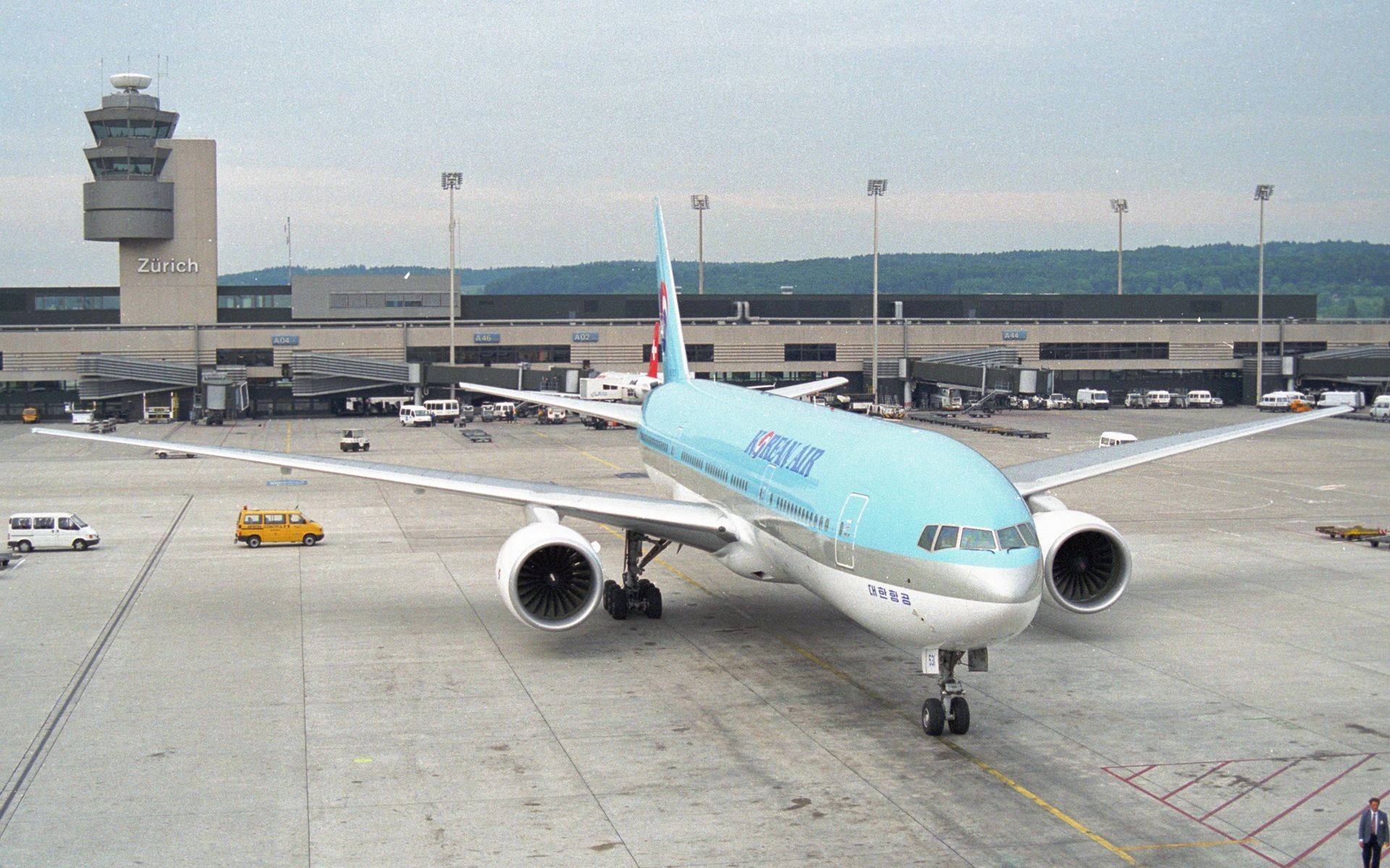 Airport 桌布 壁紙 — 大韓航空的波音777停泊在蘇黎世機場的停機坪上，背景有控制塔和遠山。