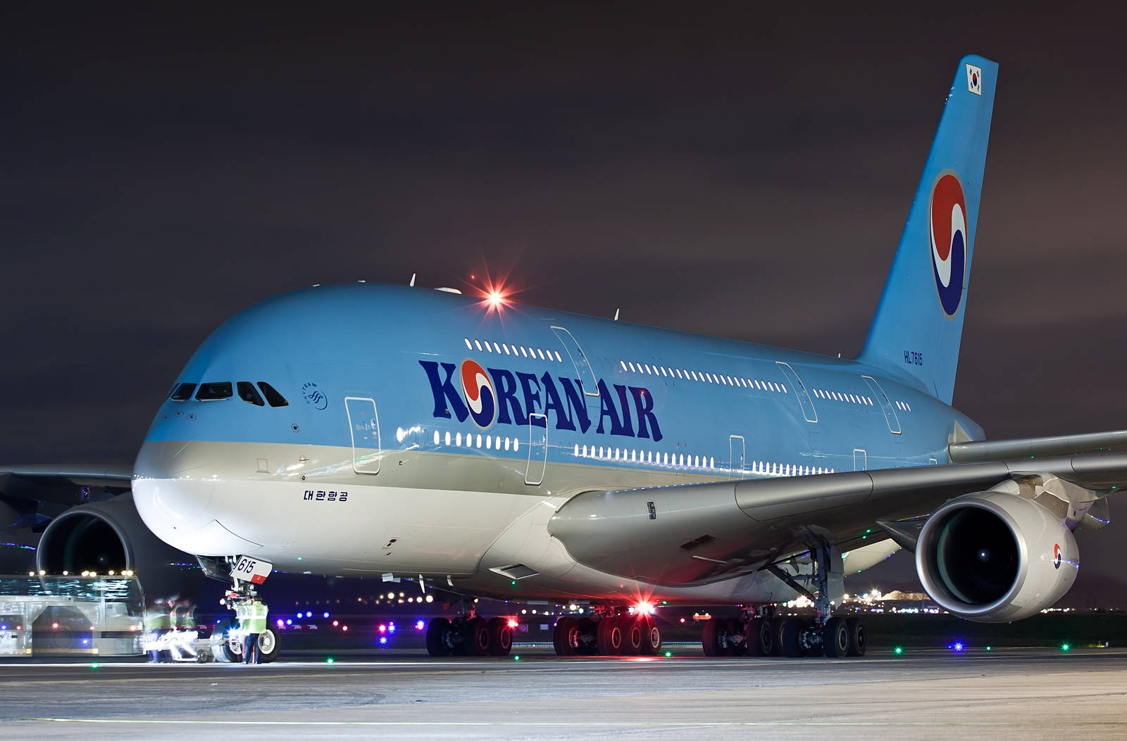 飛機 桌布 壁紙 — 大韓航空的空中巴士A380在夜間於機場停機坪上被照亮，背景是發光的燈光和漆黑的天空。