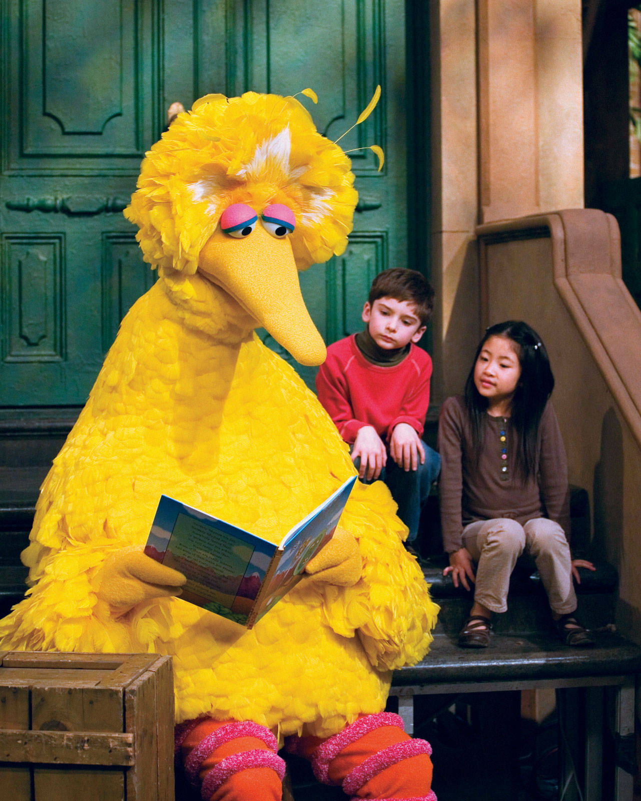Big Bird 桌布 壁紙 — 大鳥在綠色門前的階梯上為兩個孩子讀一本書。