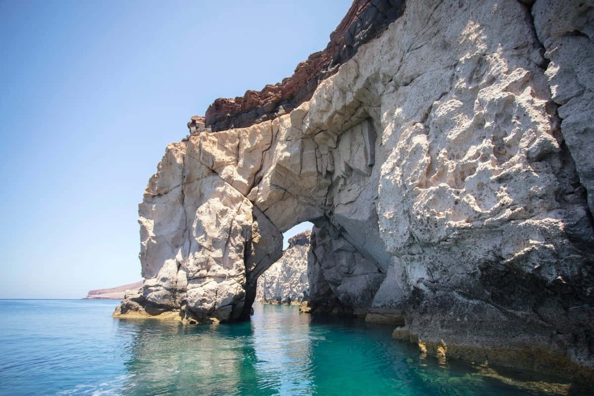 California Island 桌布 壁紙 — 天然岩石拱門框住碧綠海水，清澈藍天與崎嶇懸崖相映。
