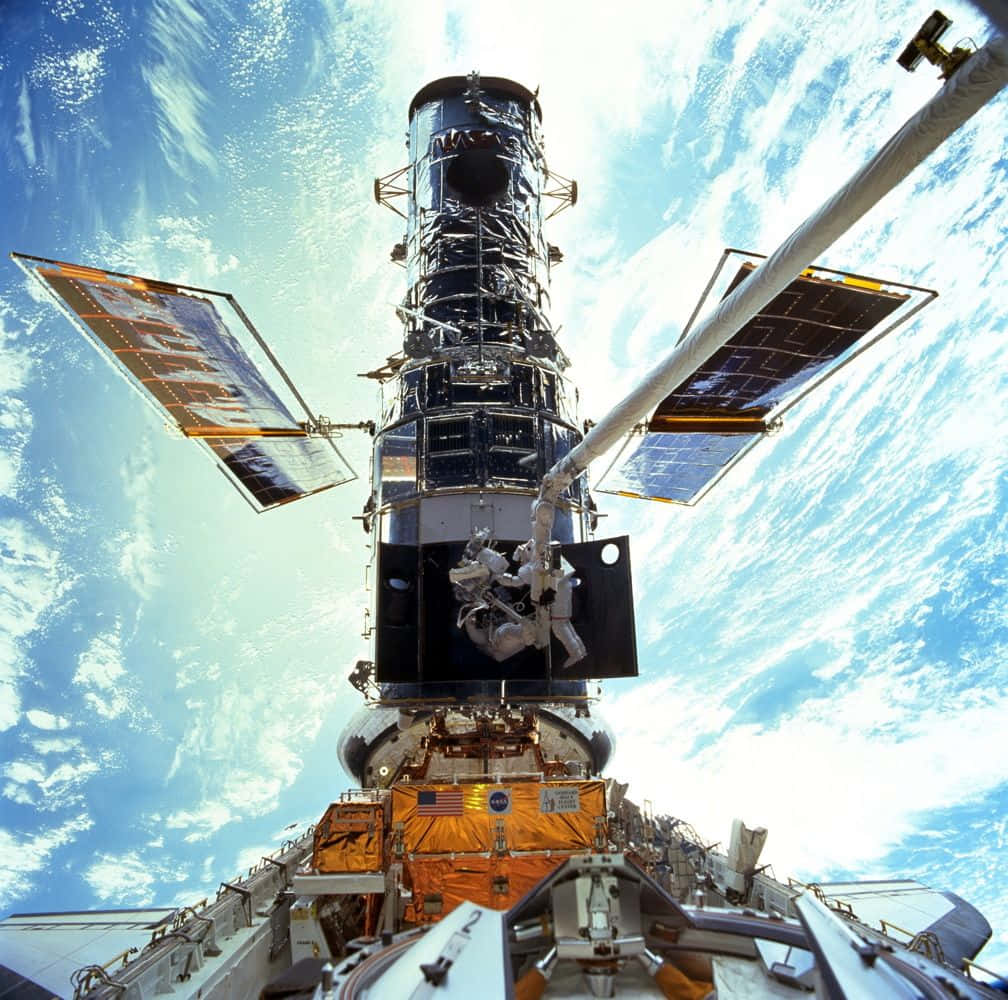 Hubble Space Telescope 桌布 壁紙 — 太空人以地球旋轉的藍白雲層為背景，修理哈伯太空望遠鏡。