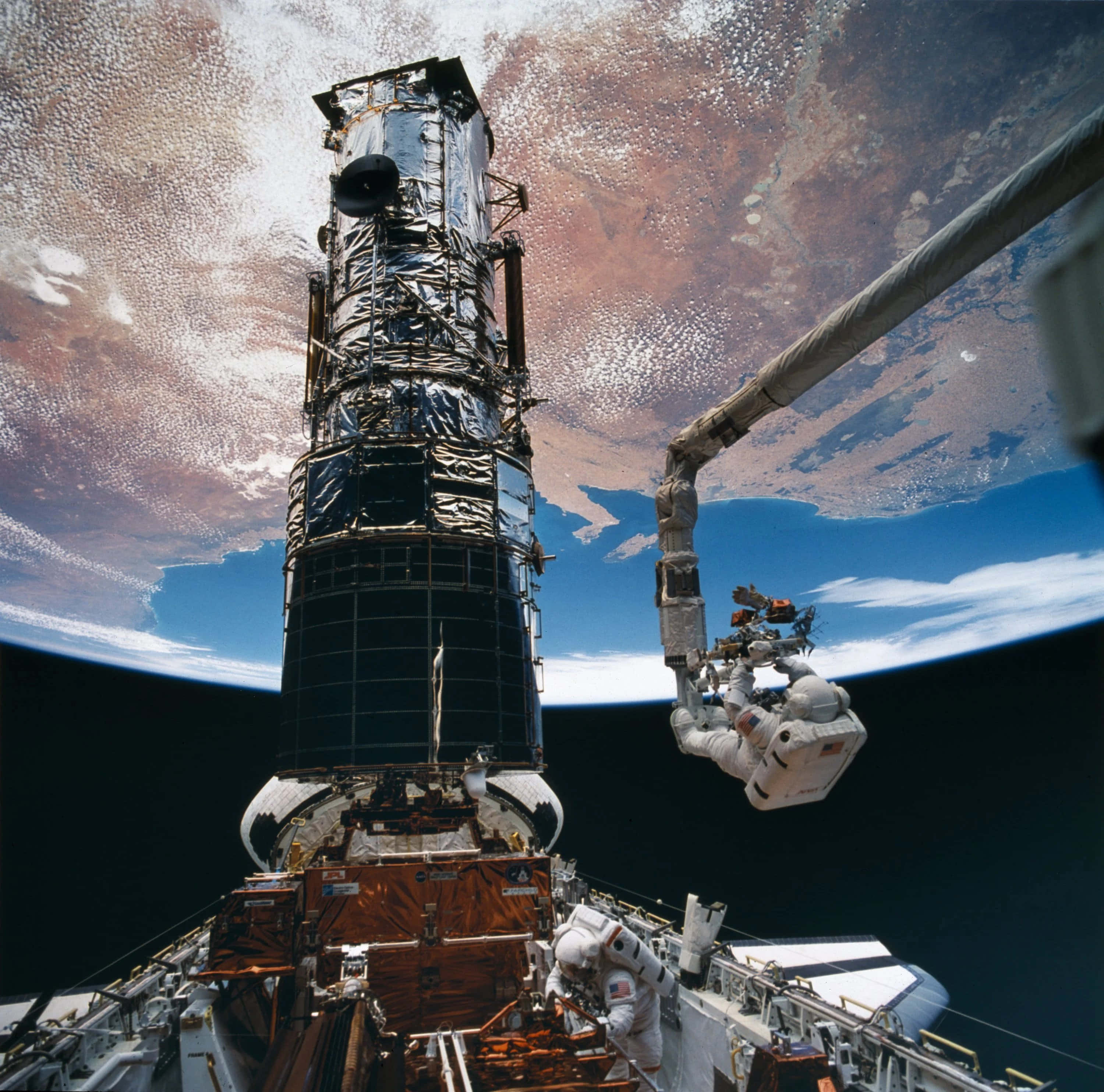 NASA 動態圖片 桌布 壁紙 — 太空人在哈伯太空望遠鏡外進行太空漫步，背景可見地球的旋轉雲層和藍色海洋。