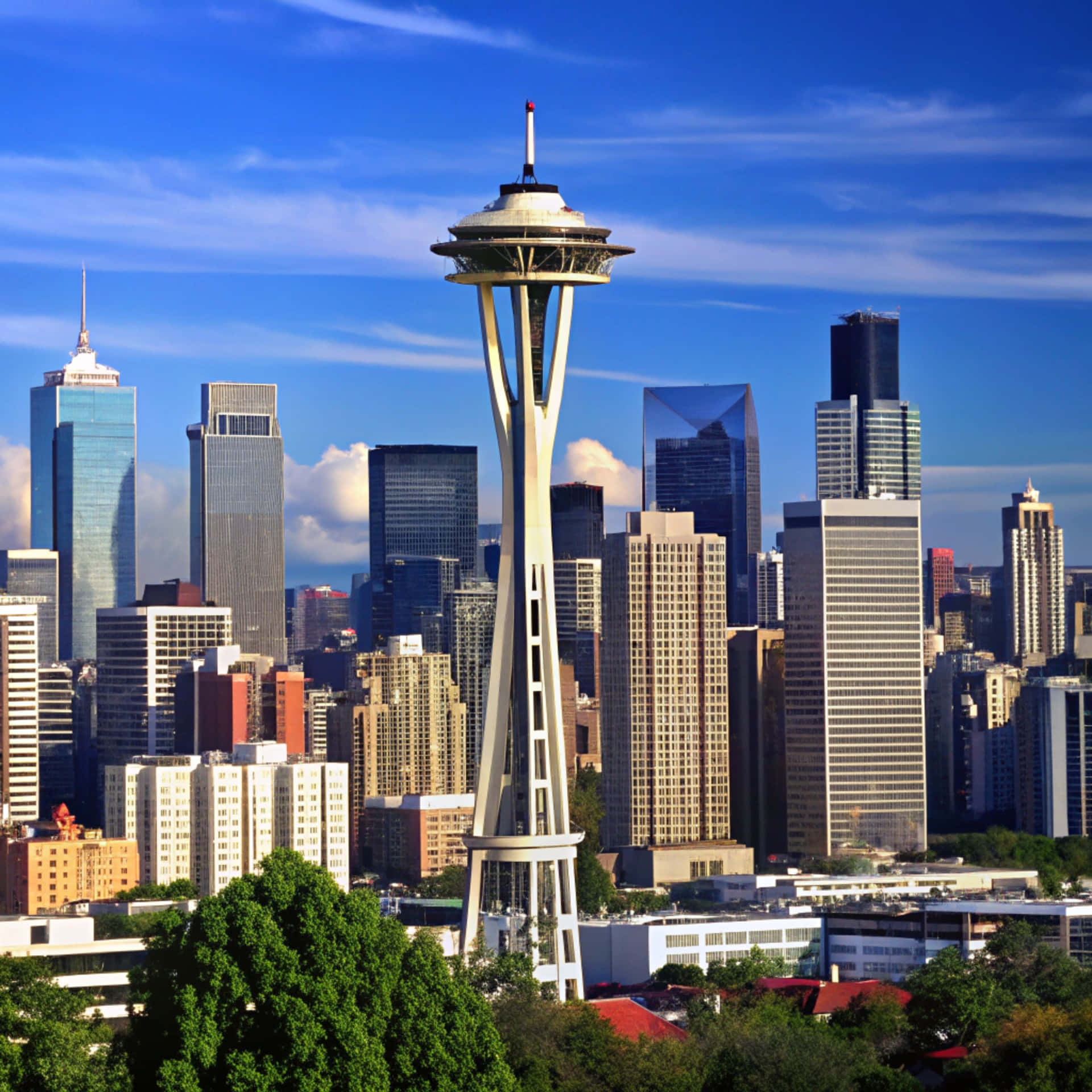 Seattle Skyline 壁紙 — 太空針塔在明亮的藍天和零星雲朵下，高聳於西雅圖的天際線之上。