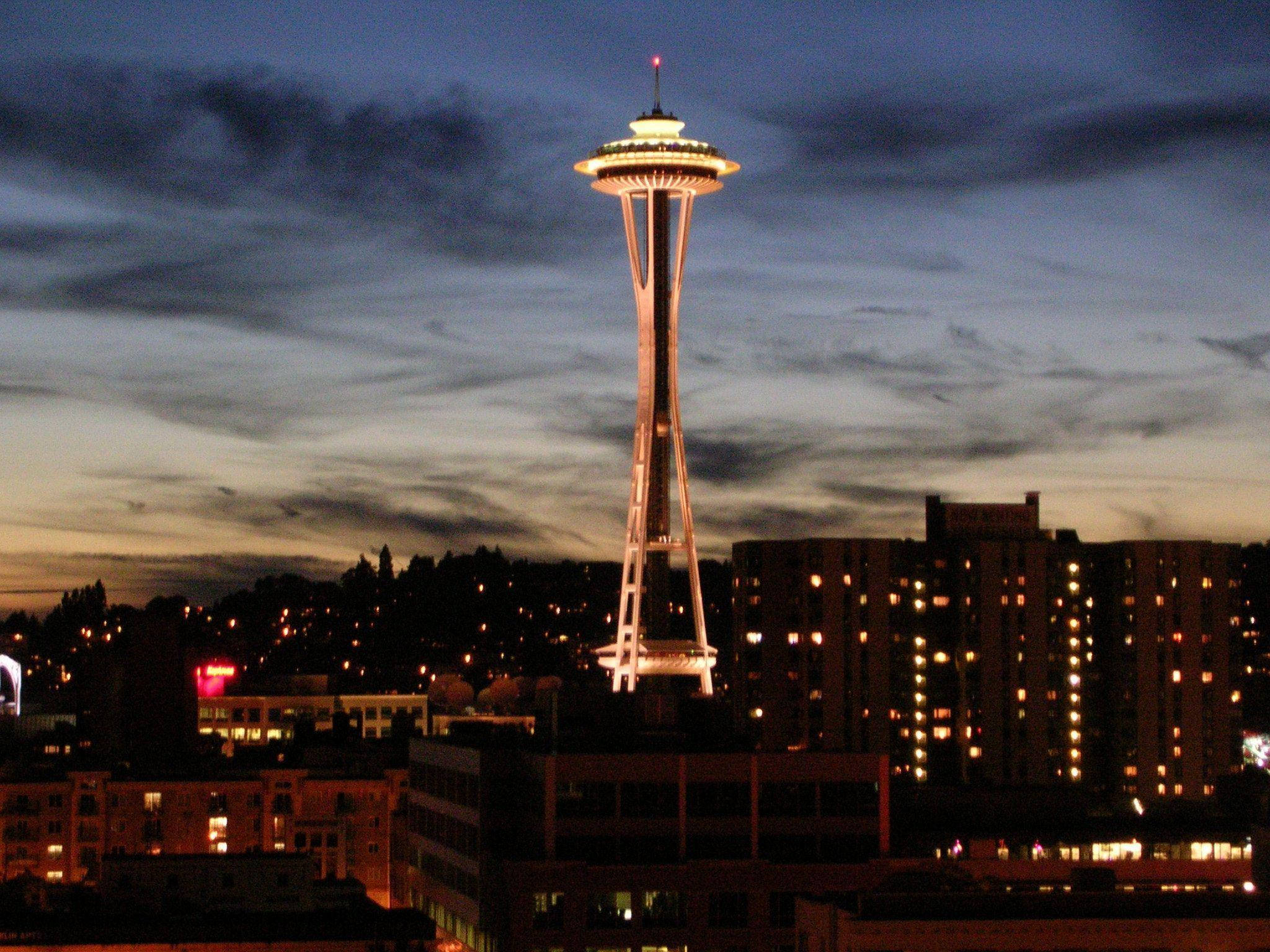 Space Needle 桌布 壁紙 — 太空針塔在暮色天空下溫暖發光，下方西雅圖的城市燈光閃爍。