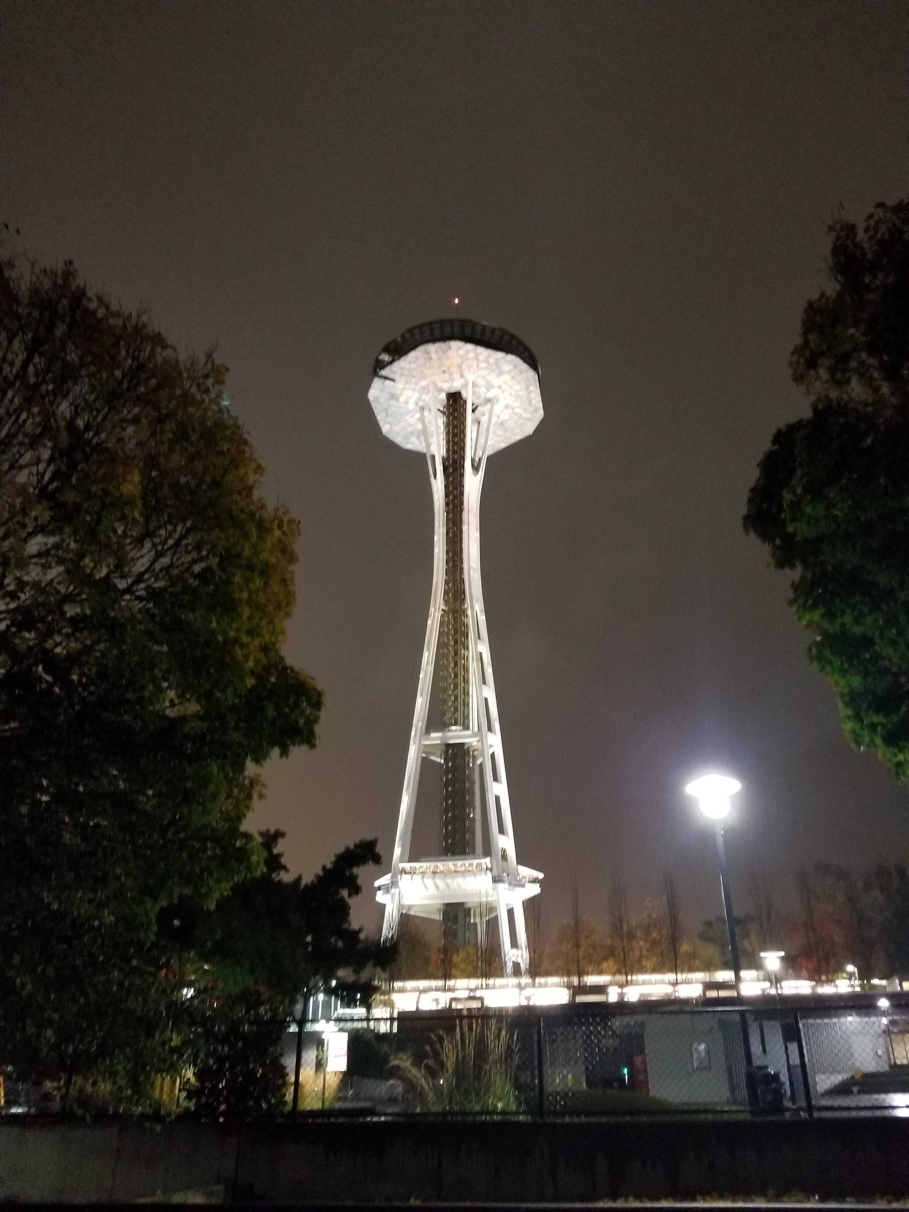 Space Needle 桌布 壁紙 — 太空針塔在漆黑的夜空下閃耀，周圍是剪影般的樹木和街燈。