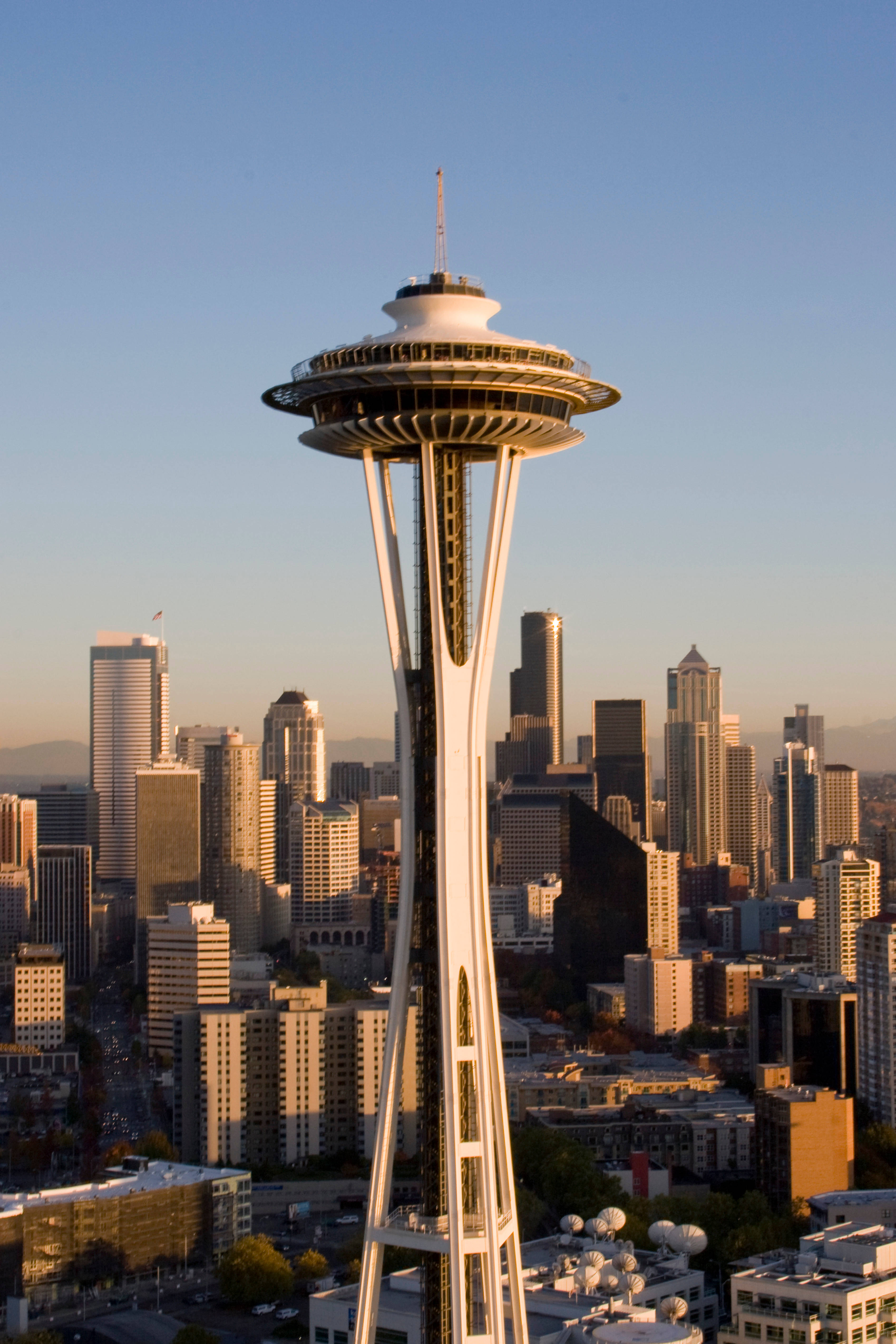 Washington 桌布 壁紙 — 太空針塔聳立在西雅圖的天際線上，沐浴在金色的日落光芒中，遠山呈現柔焦效果。