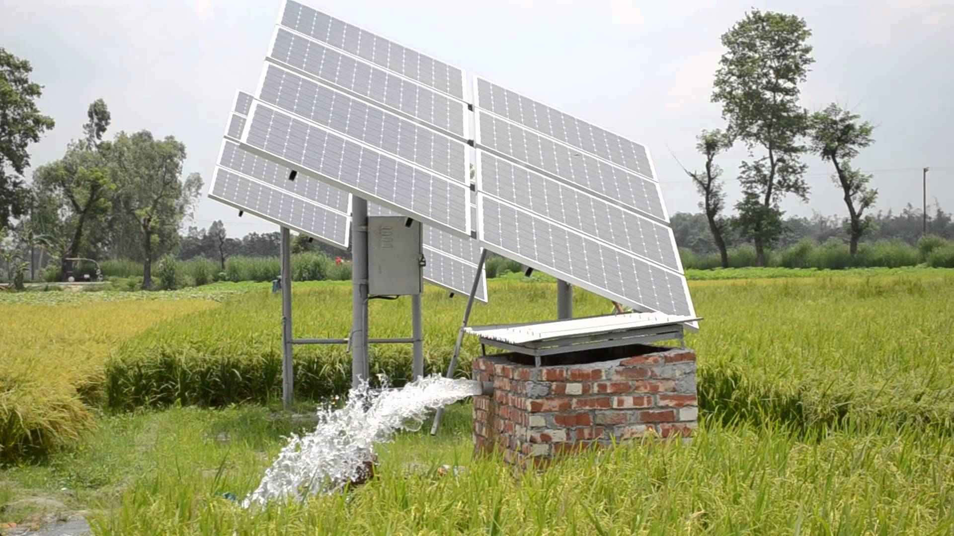 科技動圖 桌布 壁紙 — 太陽能板傾斜在一個磚砌水泵上，在明亮的天空下向茂密的綠色稻田噴水。