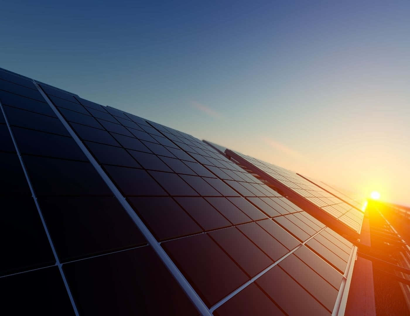 Electricity 桌布 壁紙 — 太陽能板在金色日落天空下閃耀，溫暖的光線在其深色表面上反射。