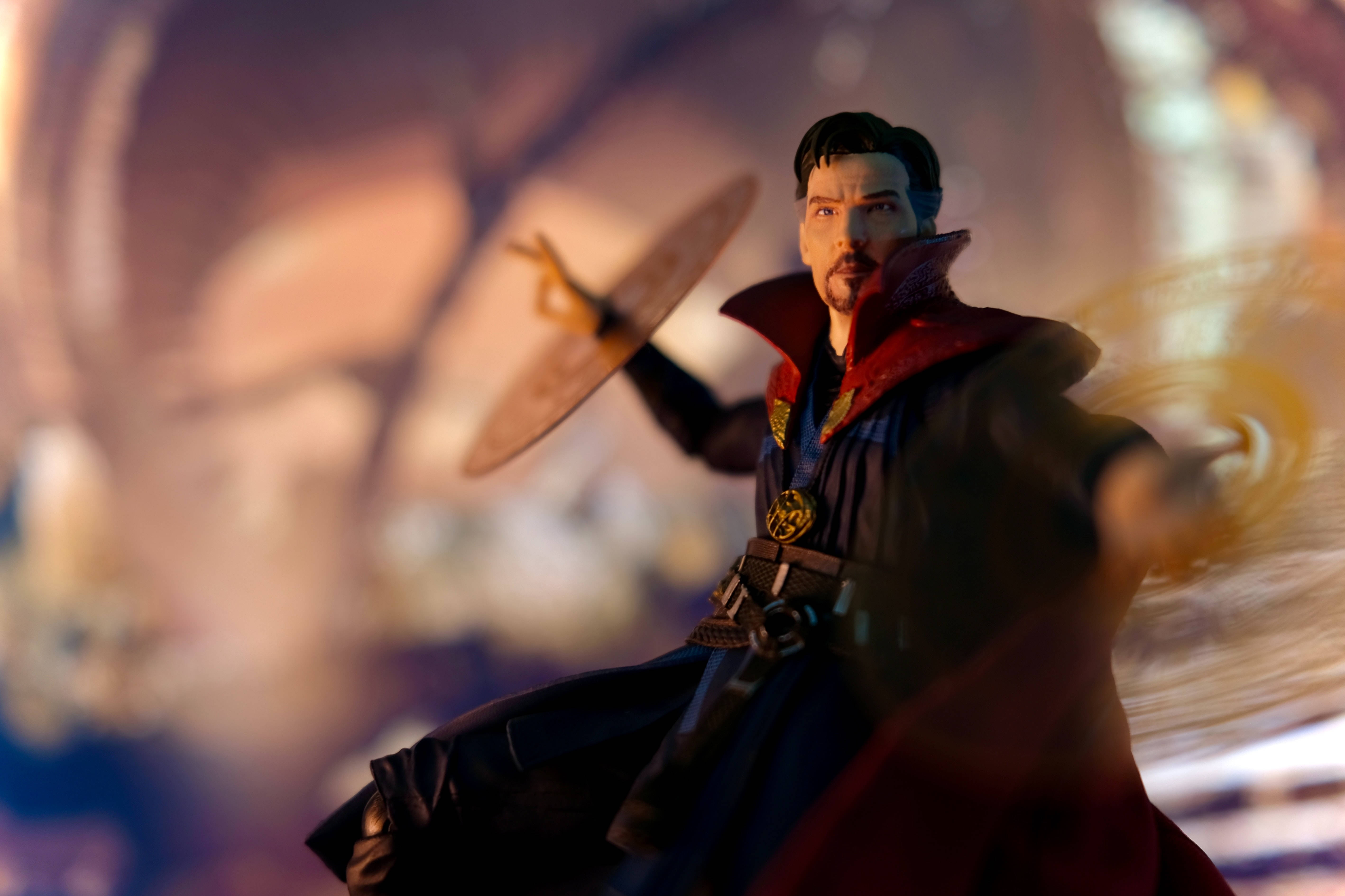 superhero supreme 桌布 壁紙 — 奇異博士身穿標誌性的紅藍長袍，在旋轉的神秘背景下伸出雙手施展發光的魔法咒語。