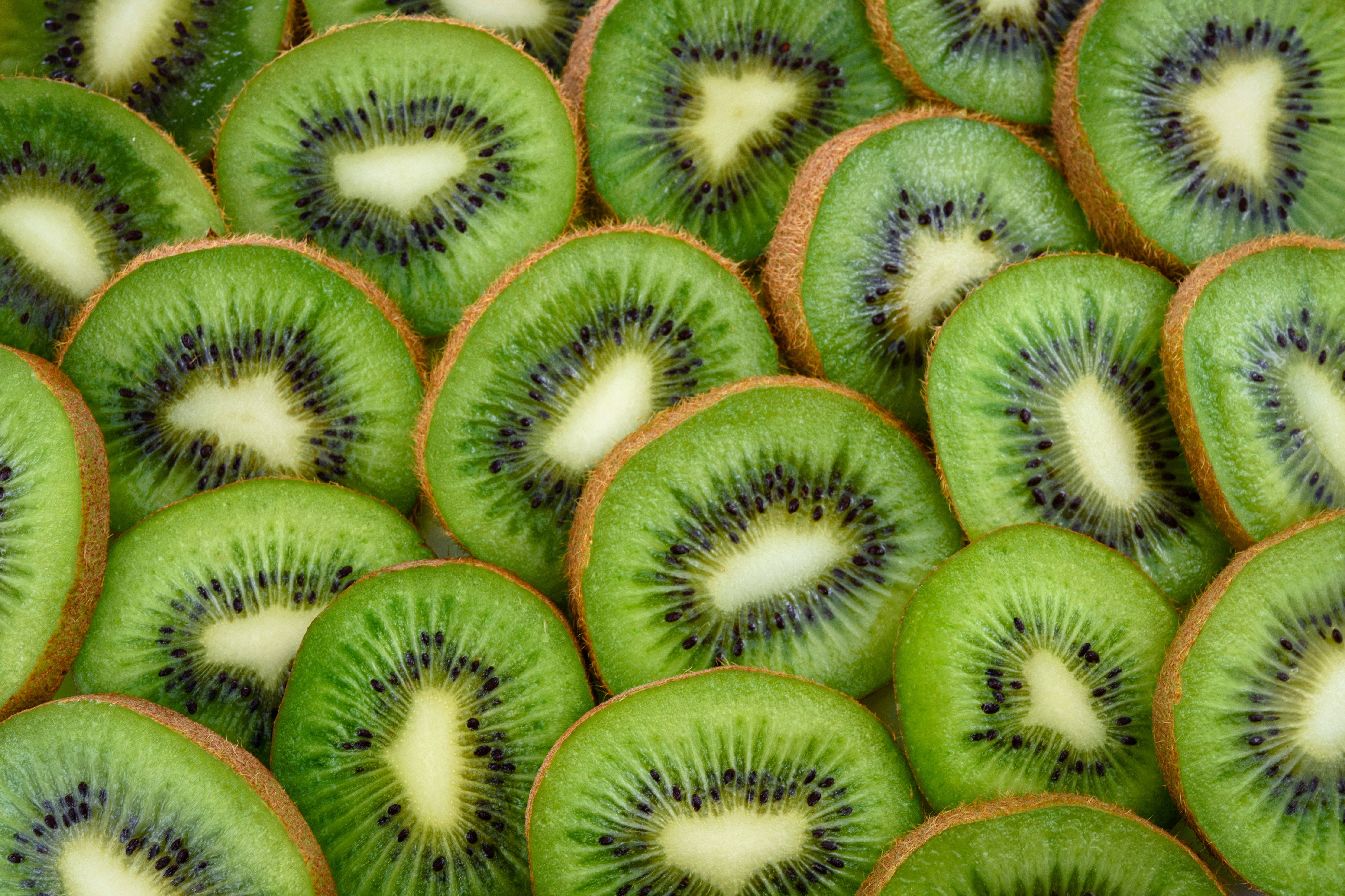 Fruit 桌布 壁紙 — 奇異果切片的鮮豔特寫，展現多汁的綠色果肉和黑色種子，形成密集圖案。