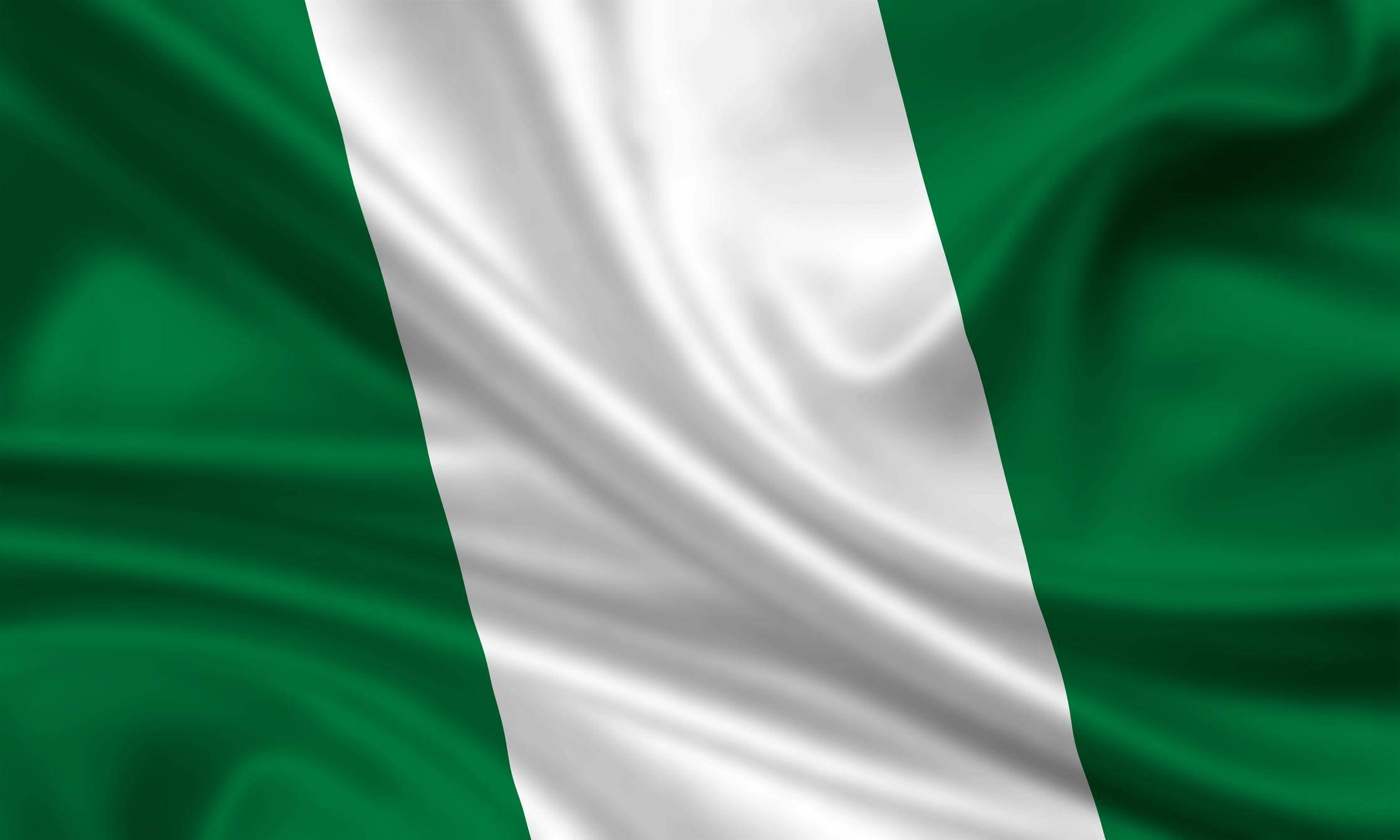 Nigeria 桌布 壁紙 — 奈及利亞國旗以綠色、白色、綠色的垂直條紋在風中動態飄揚，展現豐富的布料質感和鮮豔色彩。