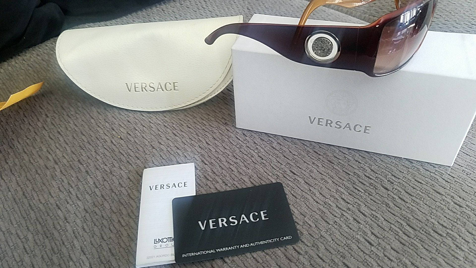 Sunglasses 桌布 壁紙 — 奢華 Versace 太陽眼鏡放置在帶有紋理的灰色表面上，位於品牌包裝之上。