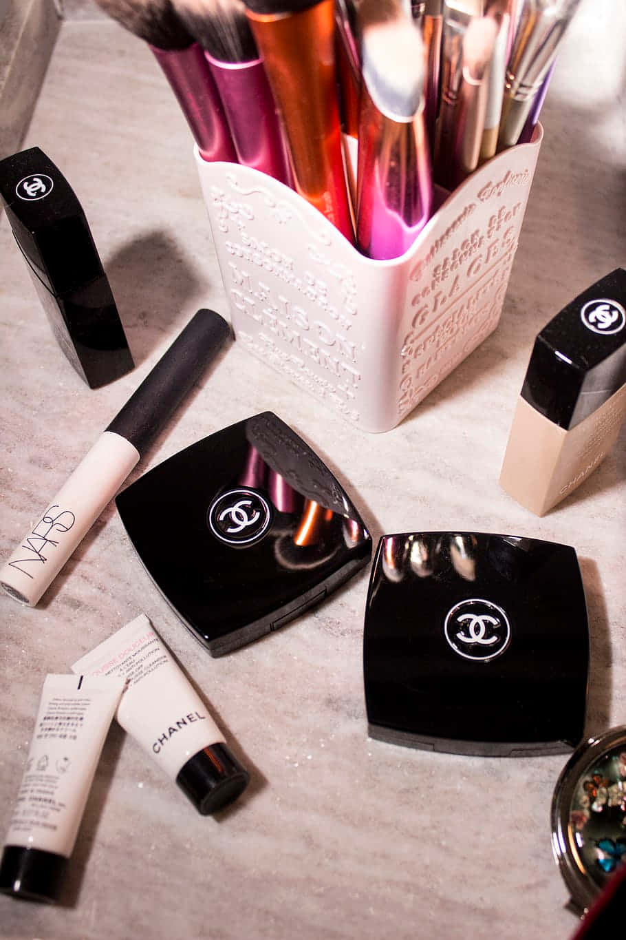 Cosmetic 桌布 壁紙 — 奢華化妝刷和Chanel化妝品在柔和溫暖的燈光下排列在大理石表面上。