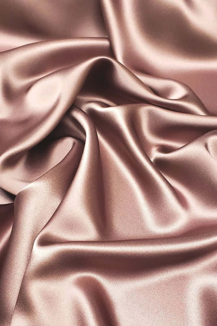 Rose Gold Color 桌布 壁紙 — 奢華玫瑰金緞面布料的特寫，帶有柔軟的皺褶和閃爍的高光。