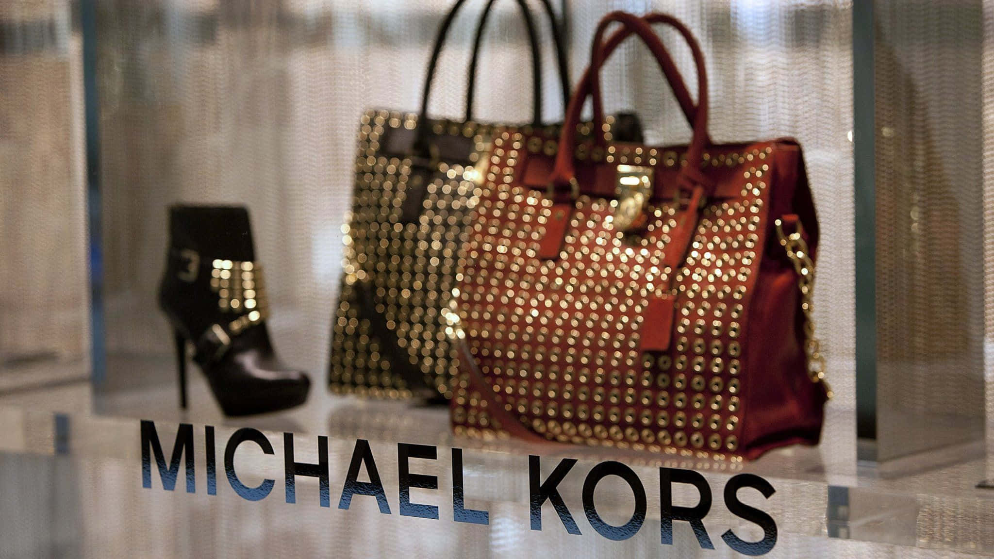 麥可·寇斯 桌布 壁紙 — 奢華的Michael Kors手提包和靴子在時尚的零售櫥窗中閃耀著金色飾釘。