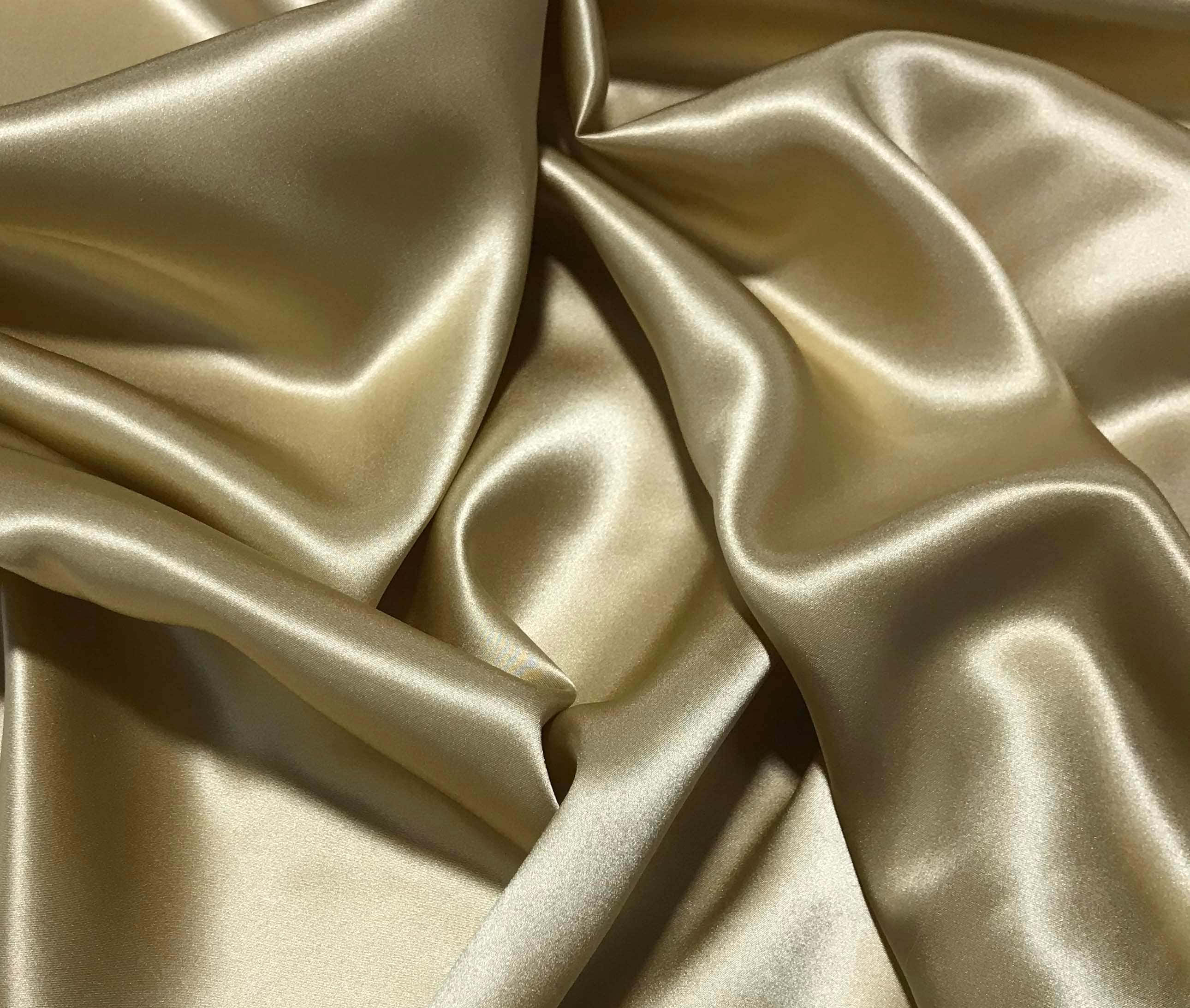 Gold Silk 桌布 壁紙 — 奢華的金色絲綢布料，在溫暖燈光下呈現柔軟褶皺和閃爍亮點。