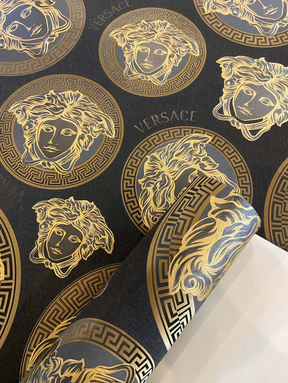versace 桌布 壁紙 — 奢華黑色壁紙，帶有金色美杜莎頭像和希臘鑰匙圖案，重複的凡賽斯設計。