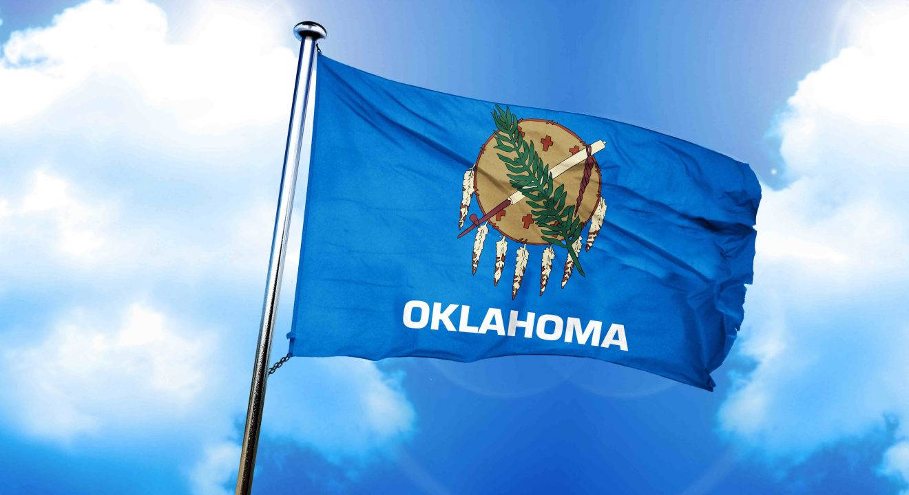 Oklahoma 桌布 壁紙 — 奧克拉荷馬州旗在明亮的藍天和蓬鬆的白雲中自豪地飄揚。
