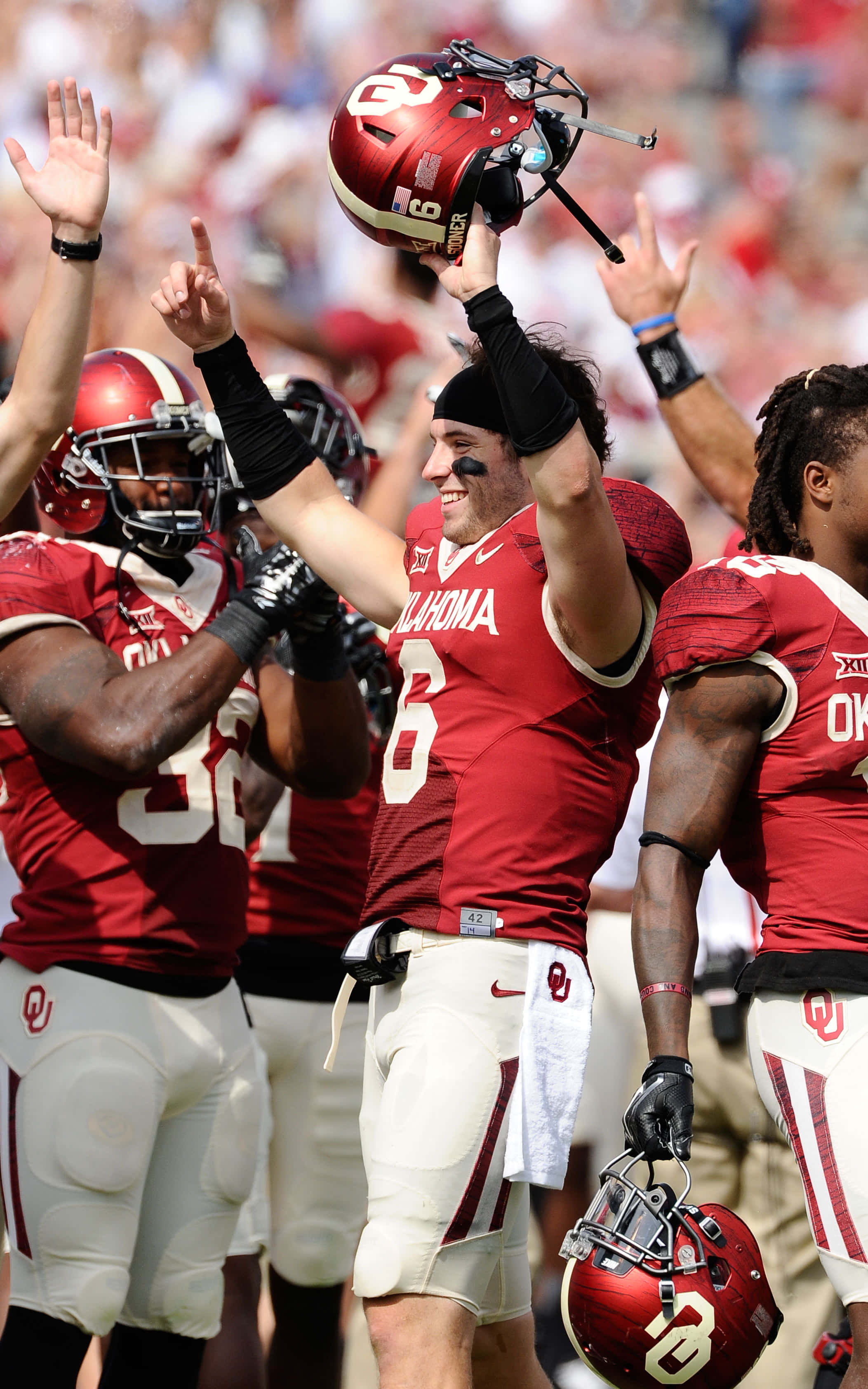 Baker Mayfield 桌布 壁紙 — 奧克拉荷馬州足球員在場上高舉頭盔、高舉雙臂慶祝勝利。