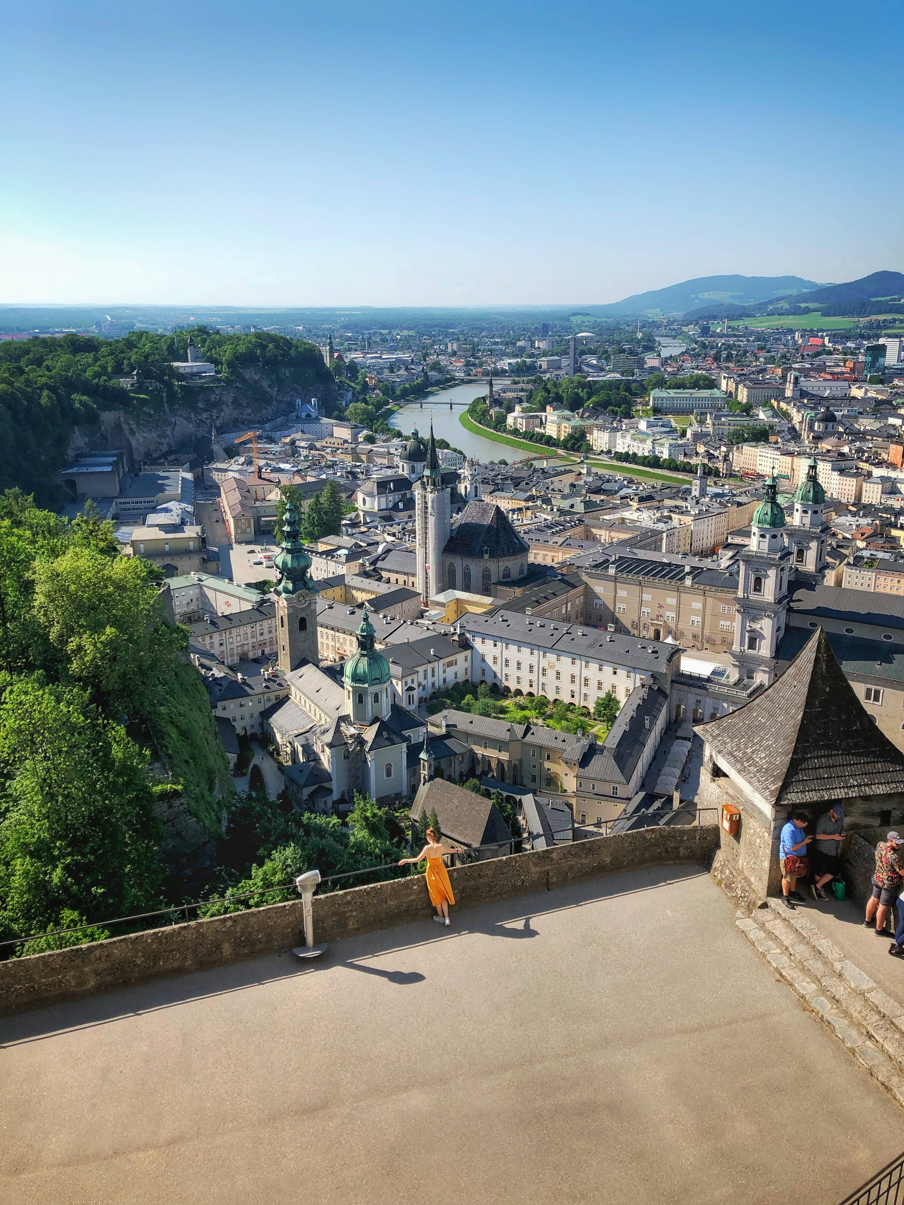 Austria 桌布 壁紙 — 奧地利薩爾茨堡充滿活力的全景景觀，展示歷史建築沿著河流蜿蜒，在清澈的藍天下。
