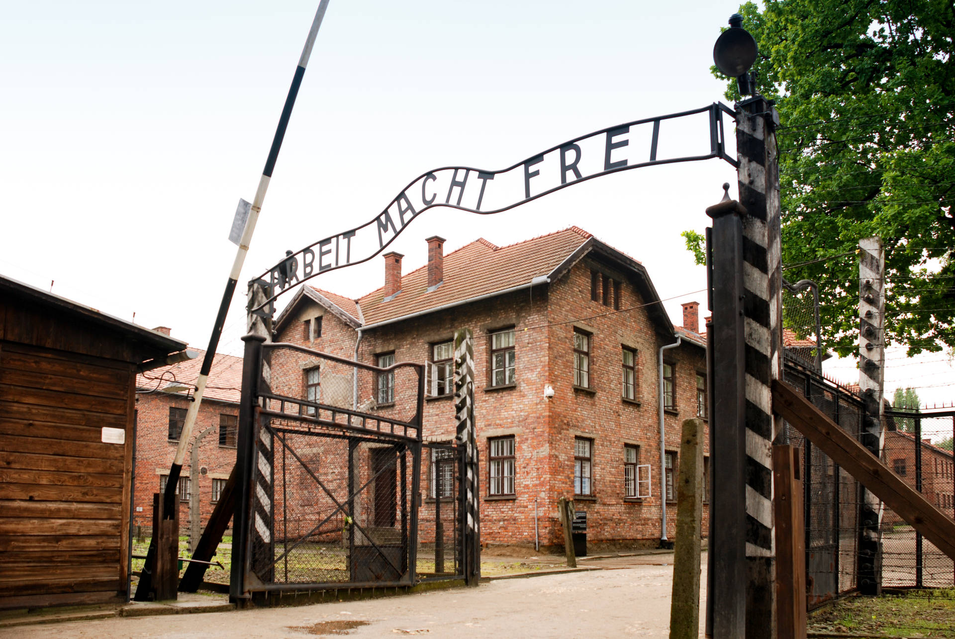 奧斯威辛集中營入口，帶有「Arbeit Macht Frei」標誌和磚砌建築。